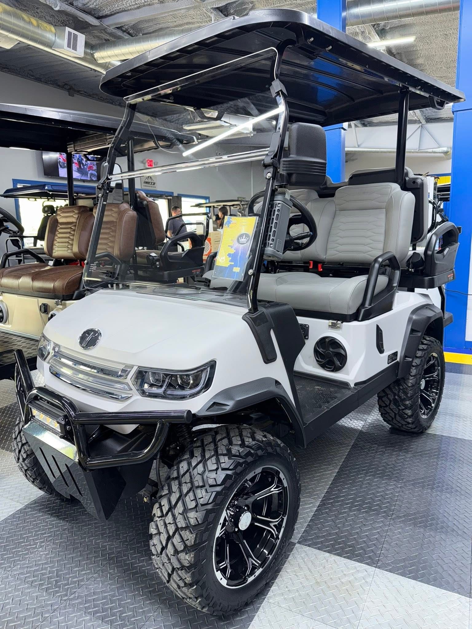 White golf cart with roof and black wheels displayed indoors in a showroom