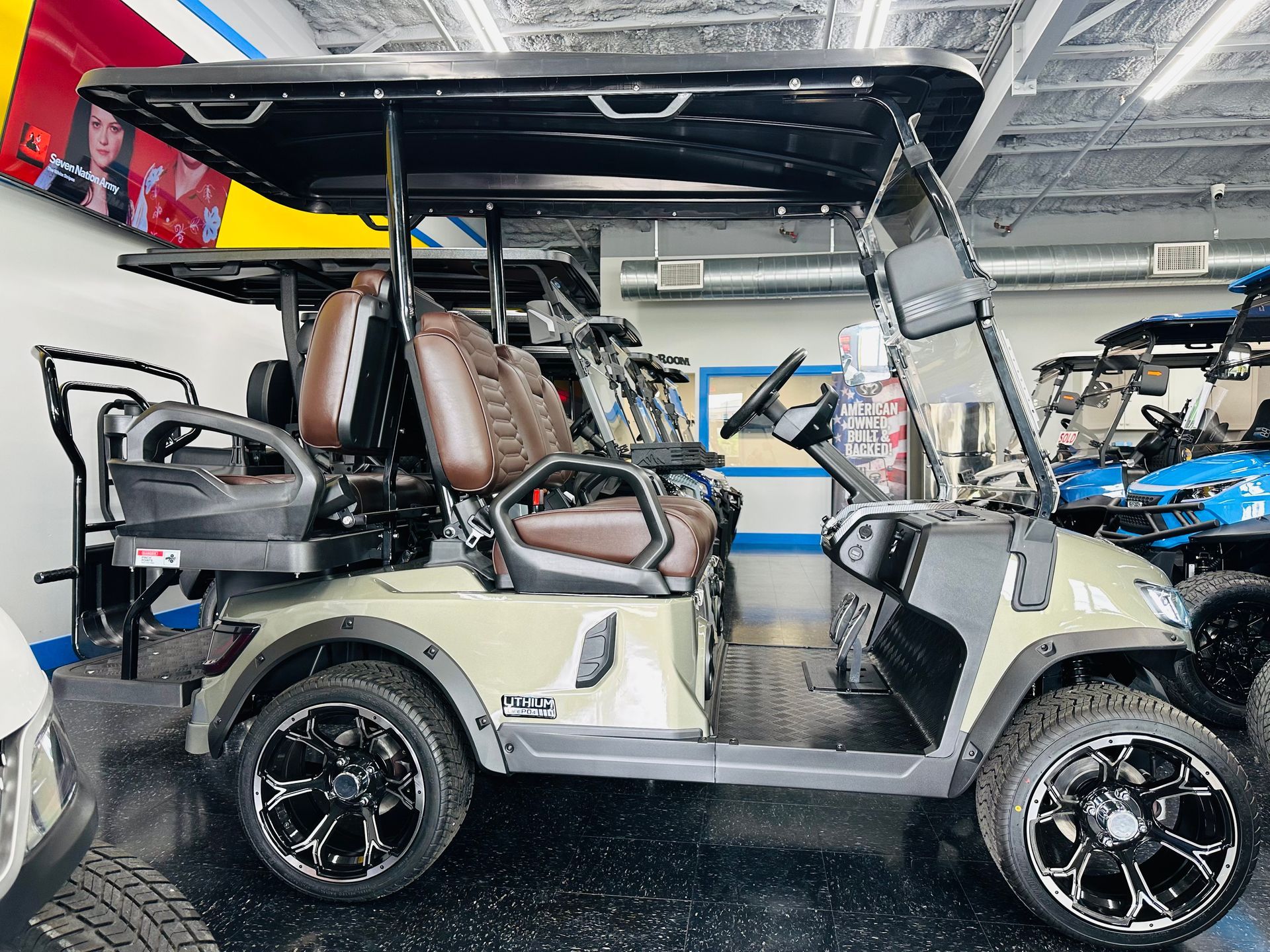 Golf cart with tan seats and open roof in an indoor showroom