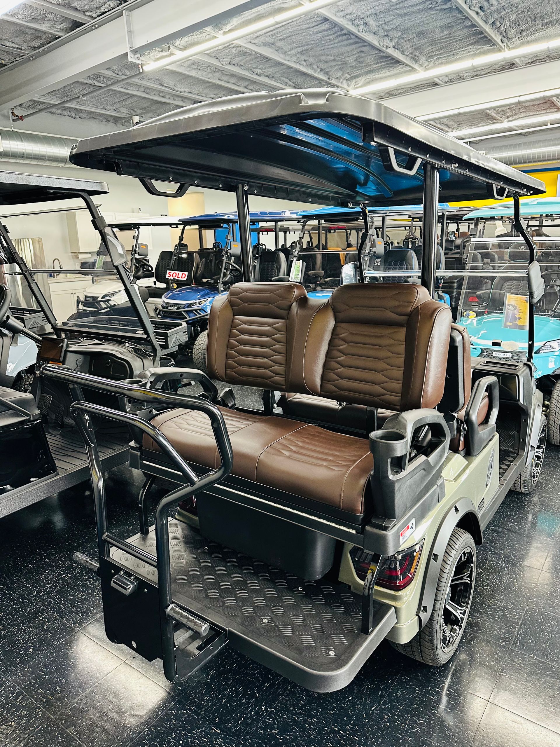 Interior of a golf cart with brown seats and a black roof in a workshop, surrounded by foam and equipment.