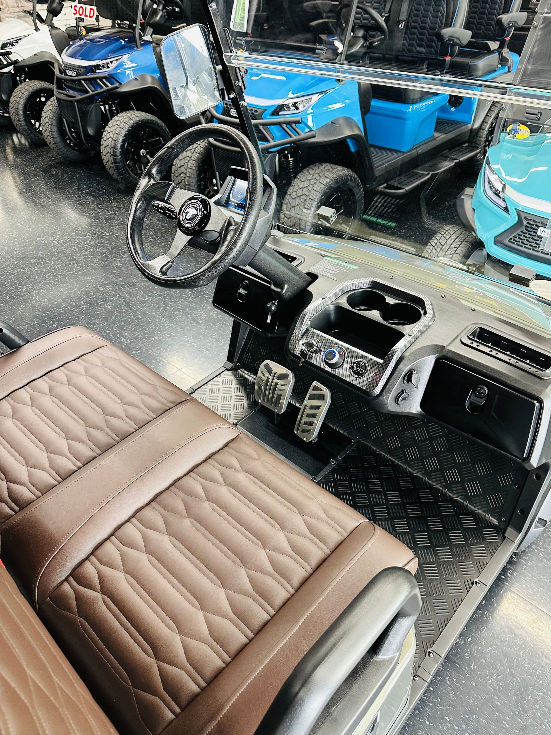 Brown tractor seat and steering console in the foreground, with blue tractors parked behind them.