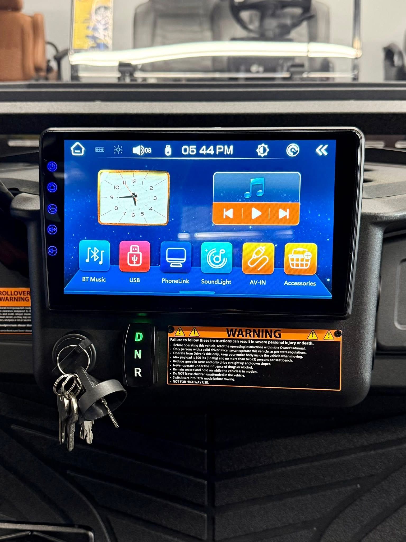Car dashboard with an aftermarket touchscreen showing app icons and climate controls, keys hanging below.
