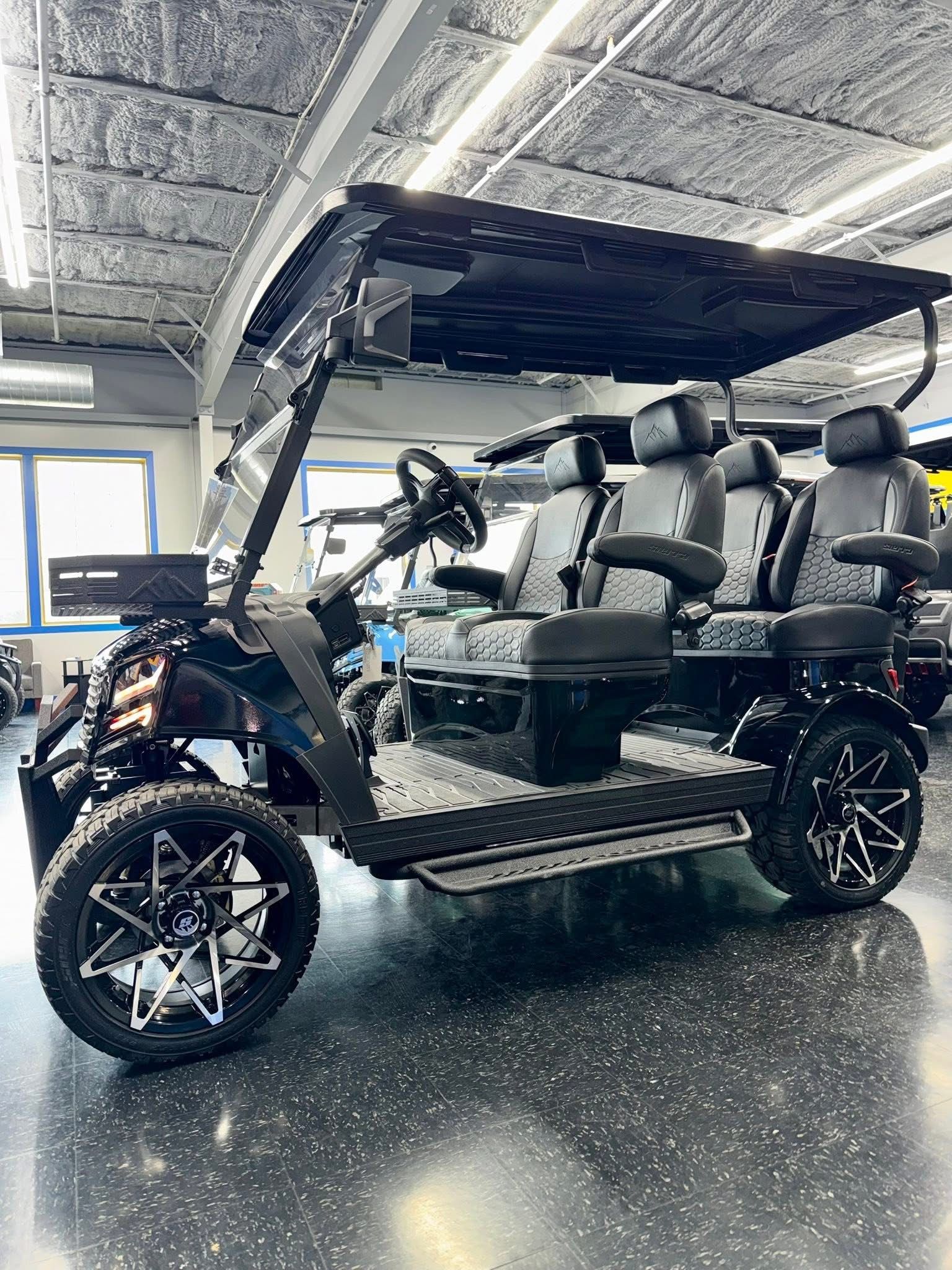 Black six-seat off-road golf cart with lifted suspension and roof, parked indoors on polished concrete.