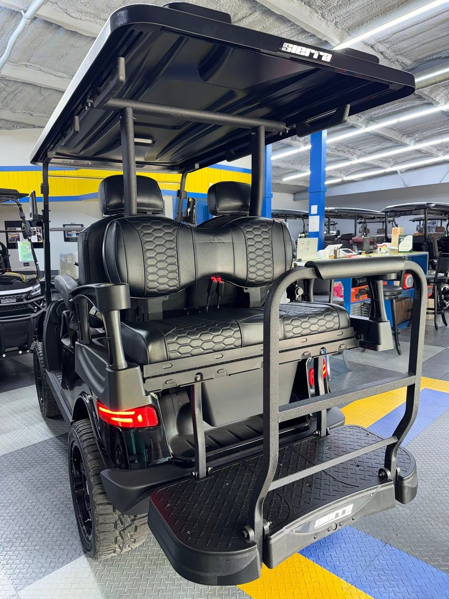 Off-road vehicle with open roof and rear-mounted spare tires in a garage or workshop