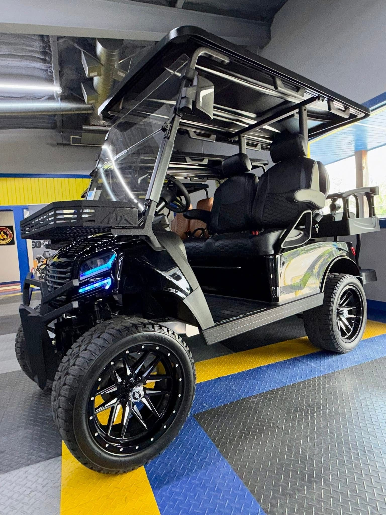 Custom black golf cart with blue LED lights, parked indoors on a blue and gray floor.