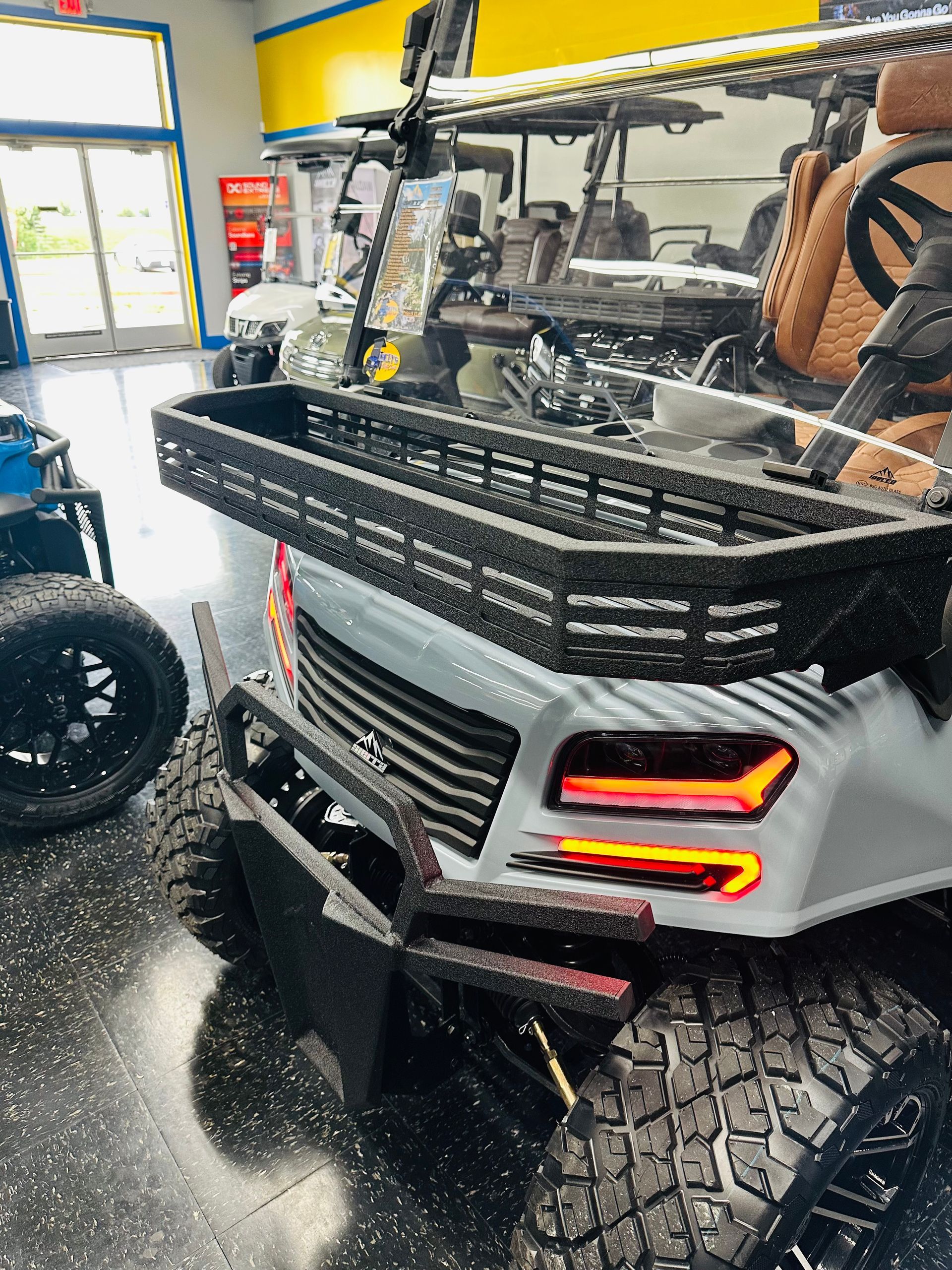 Custom off-road vehicle with roof rack, large tires, and red LED taillights in a garage