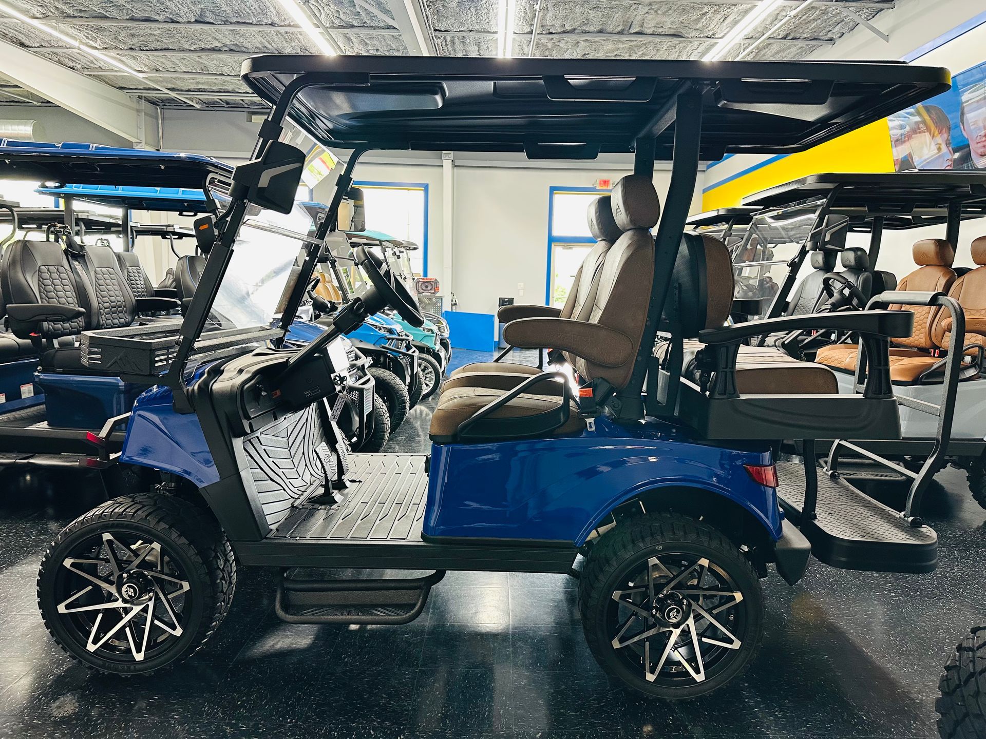 Blue golf cart in a showroom with other carts in the background.