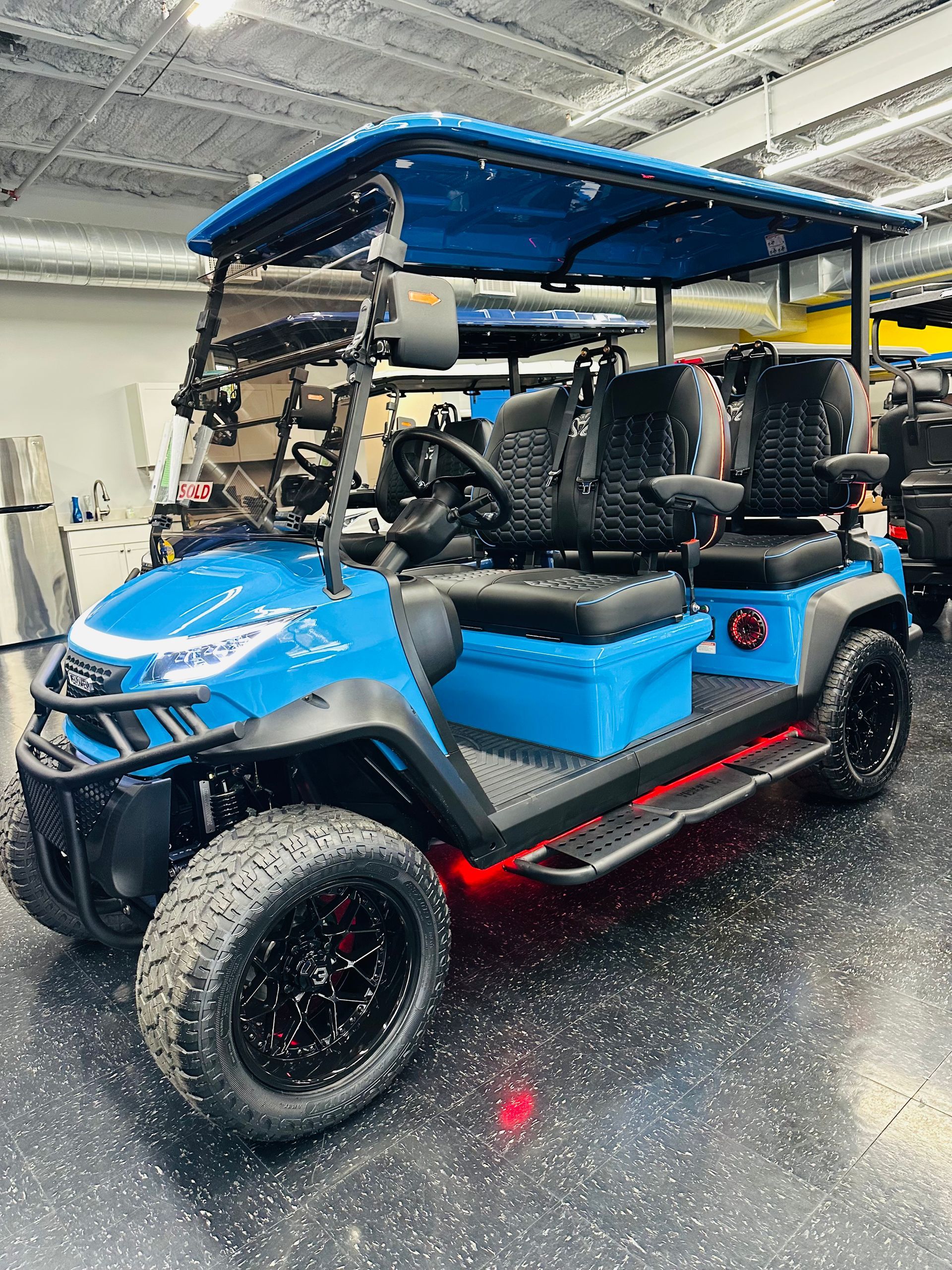 Blue golf cart with canopy parked indoors on a wet floor under bright lights