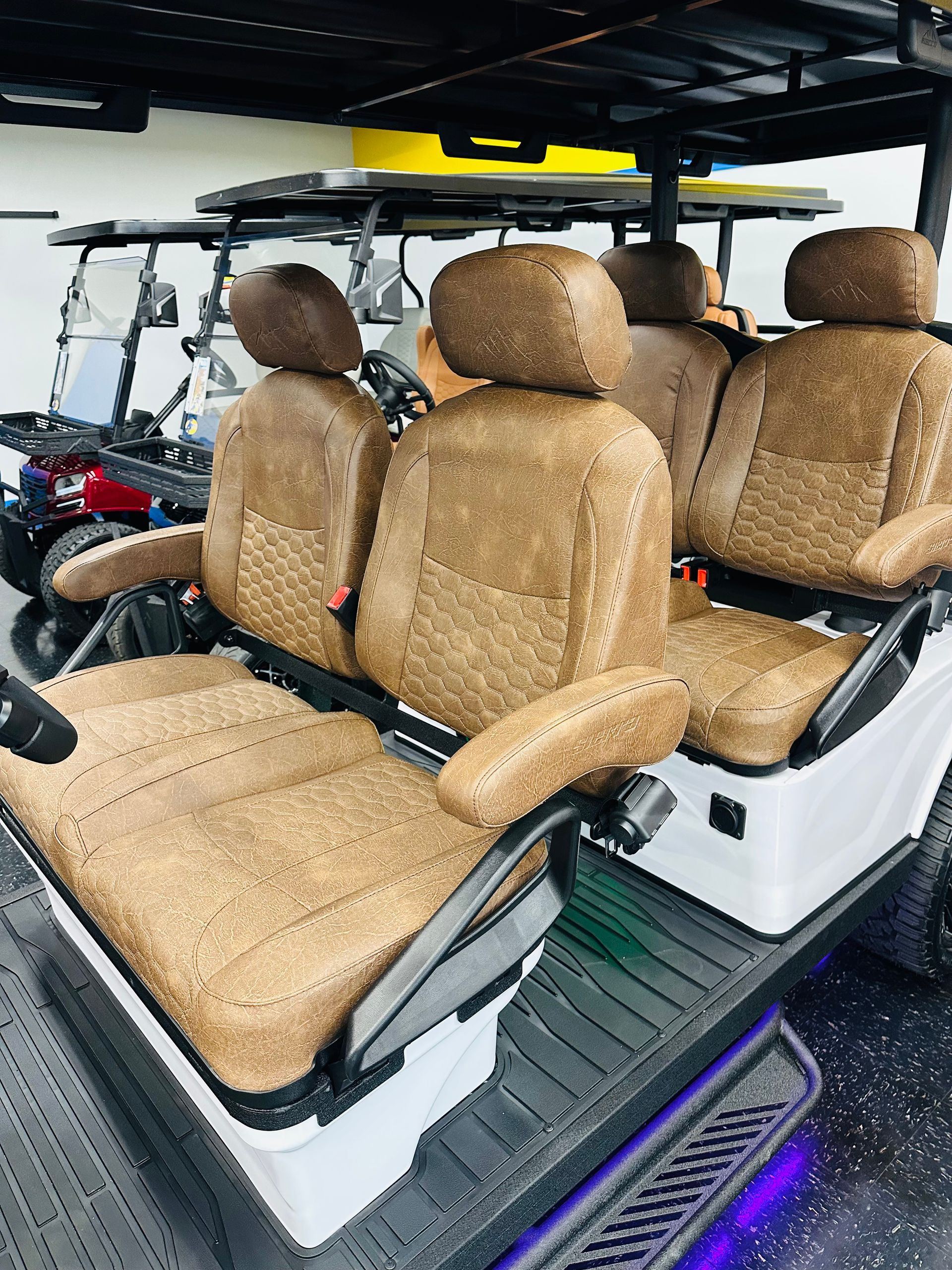 White golf cart with tan seats and roof, shown from the side with purple underglow lights.