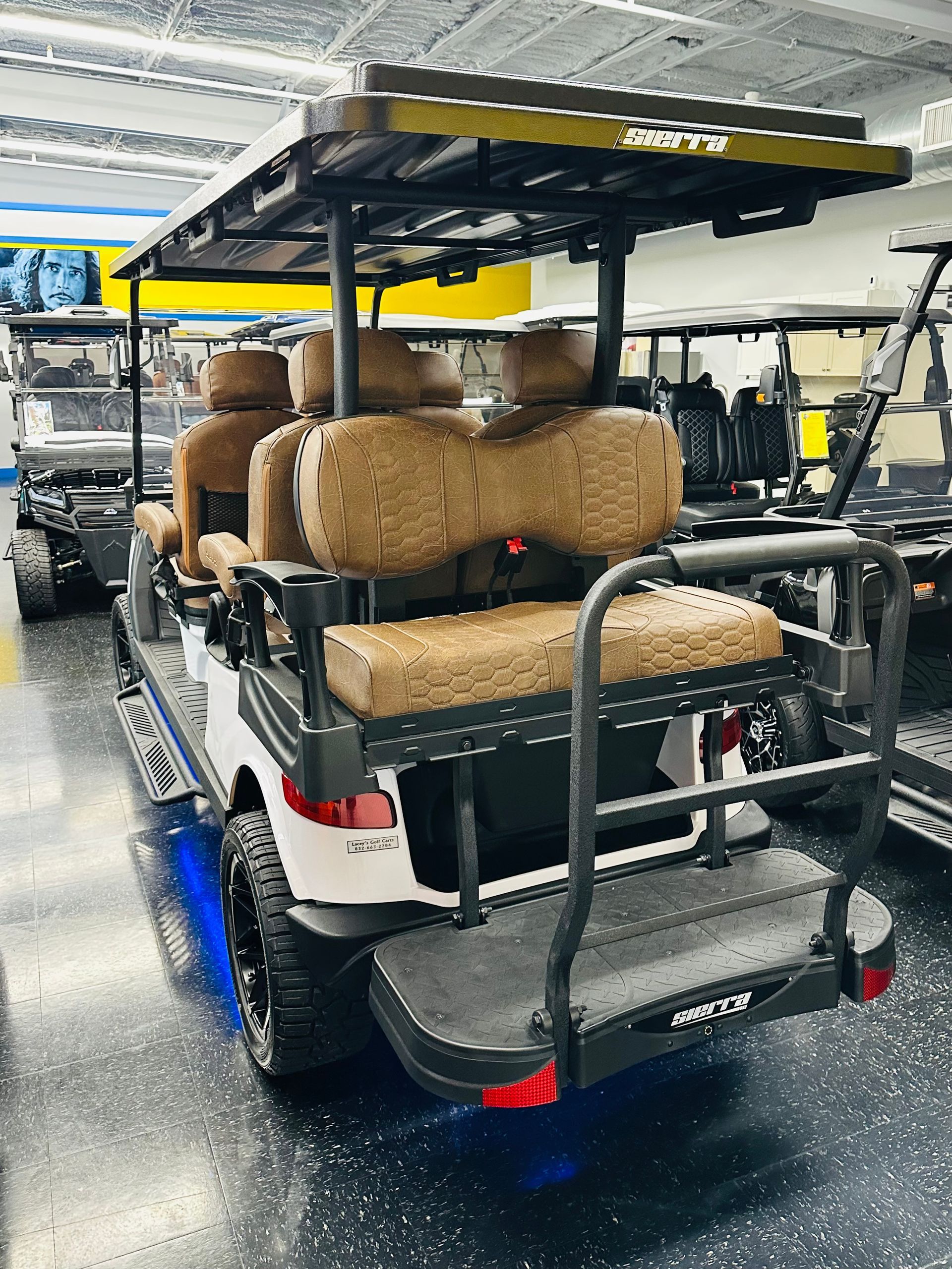 Modified off-road golf cart with tan cushions parked indoors on a wet floor.