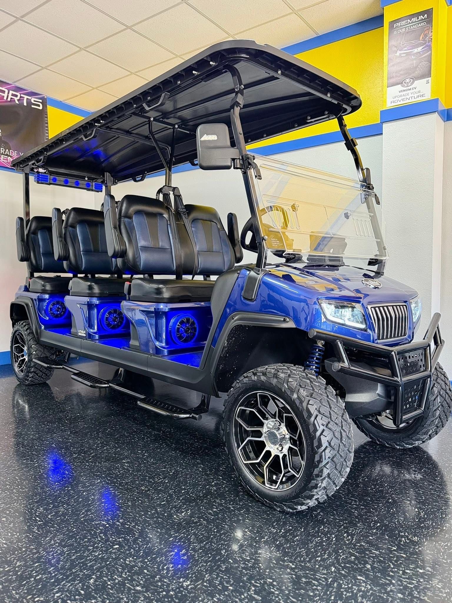 Blue off-road golf cart with glowing underlights parked indoors on a speckled floor.