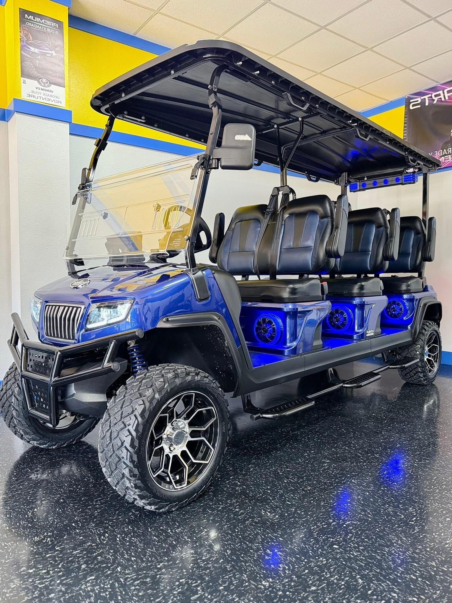 Blue off-road golf cart with black roof and seats in a showroom on a glossy speckled floor