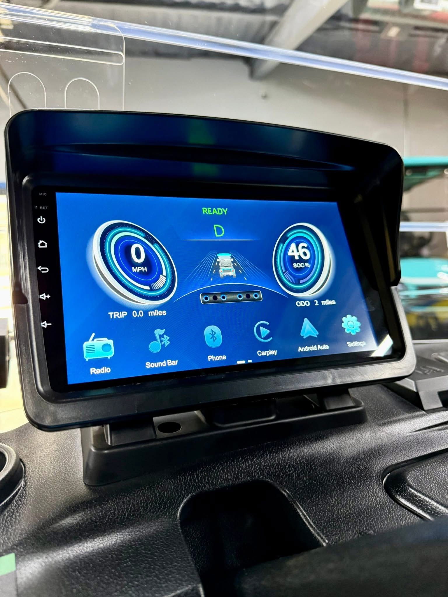 Car dashboard display showing a blue digital driving interface with speed, range, and media icons