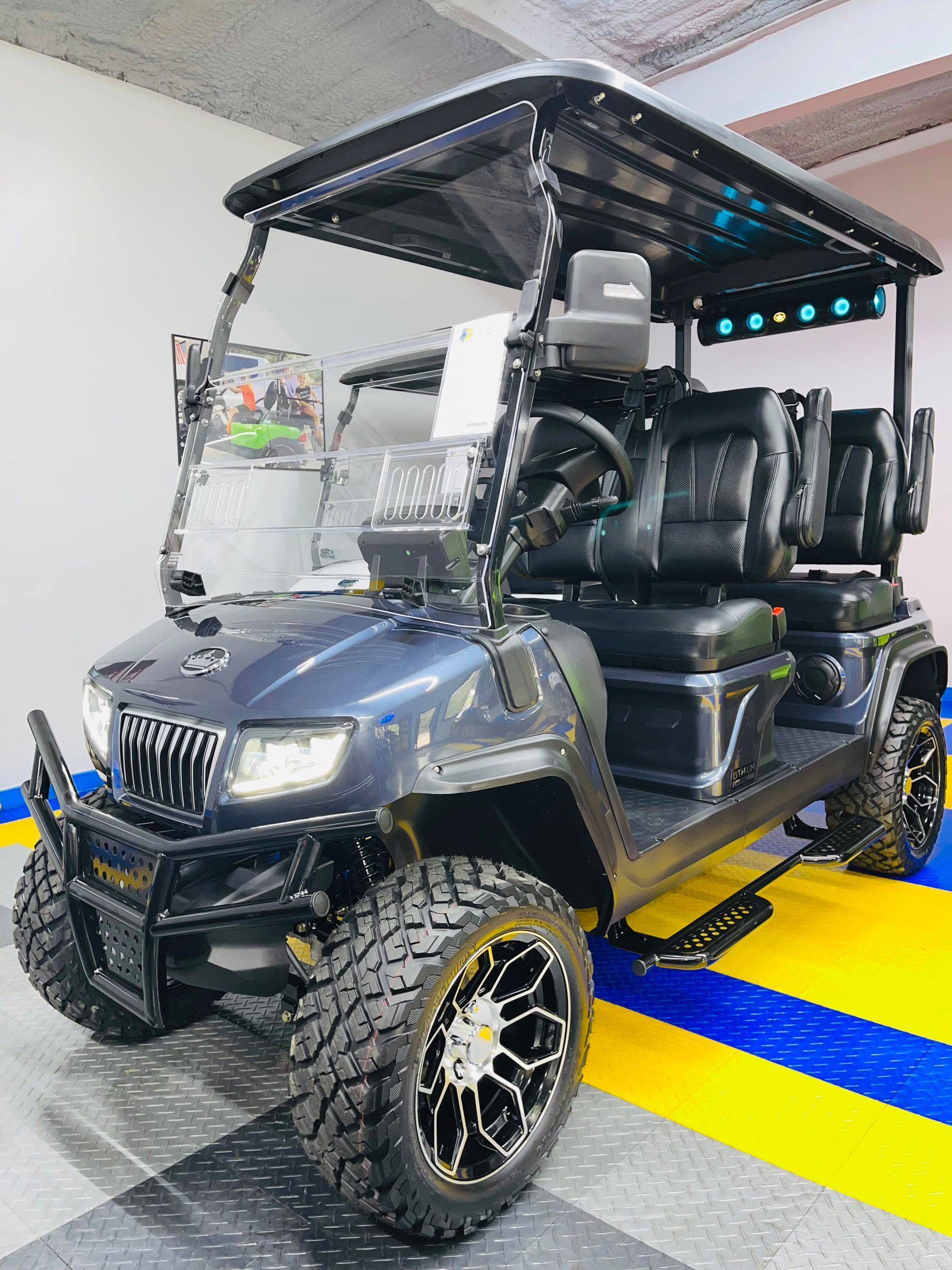 A black golf cart is parked on a checkered floor in a garage.