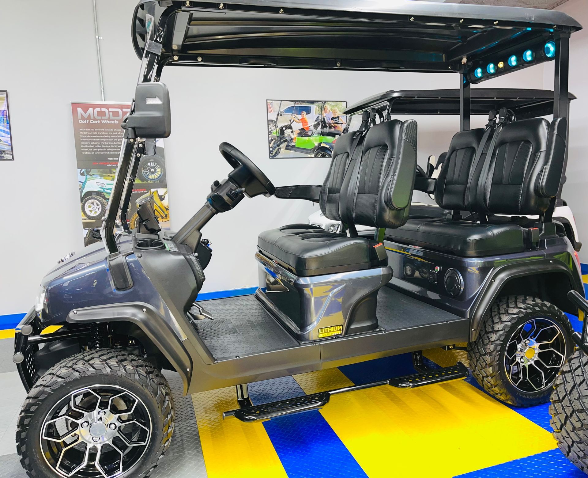 A black golf cart is parked on a yellow and blue floor.
