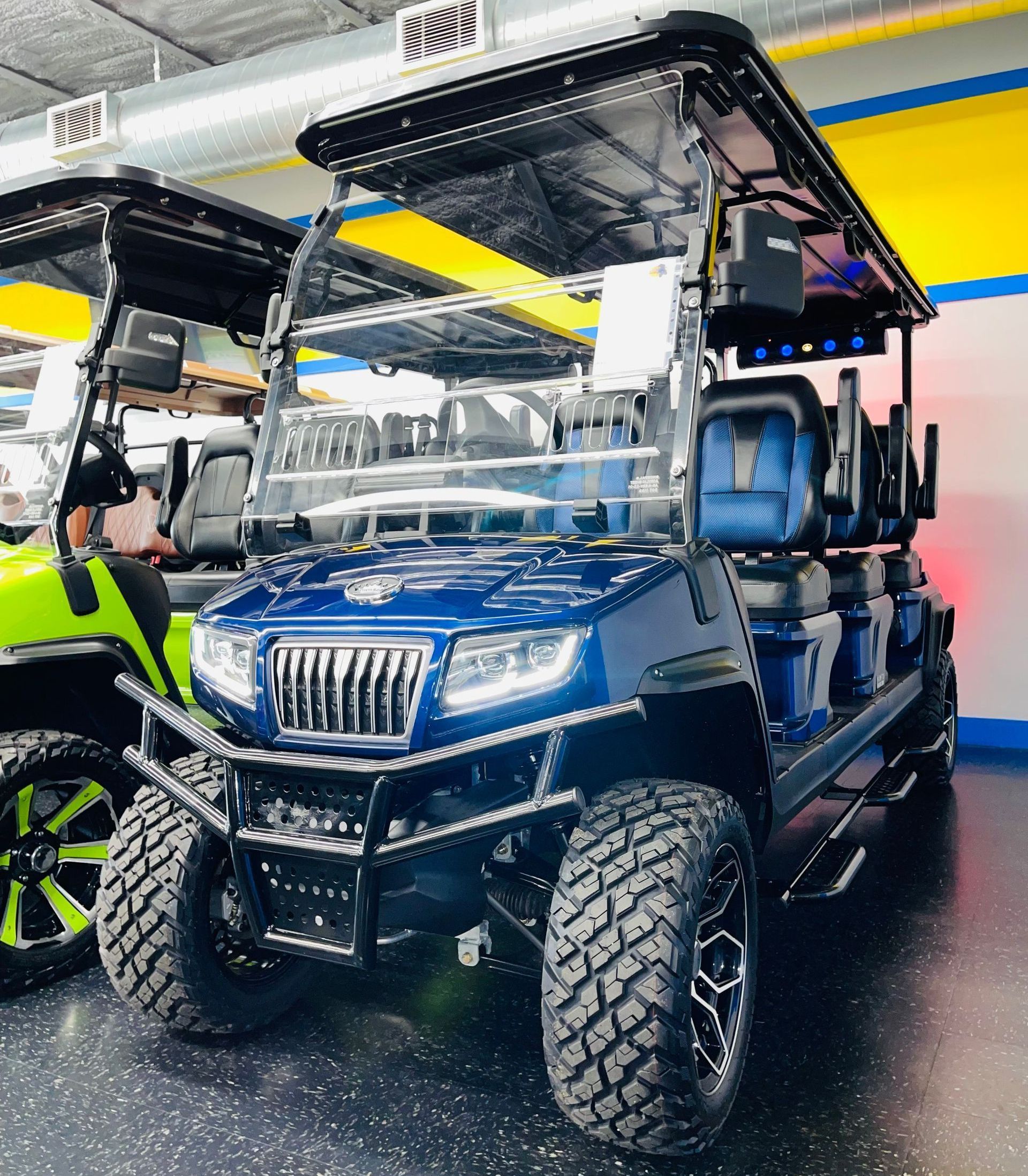 A blue golf cart is parked next to a green golf cart in a showroom.