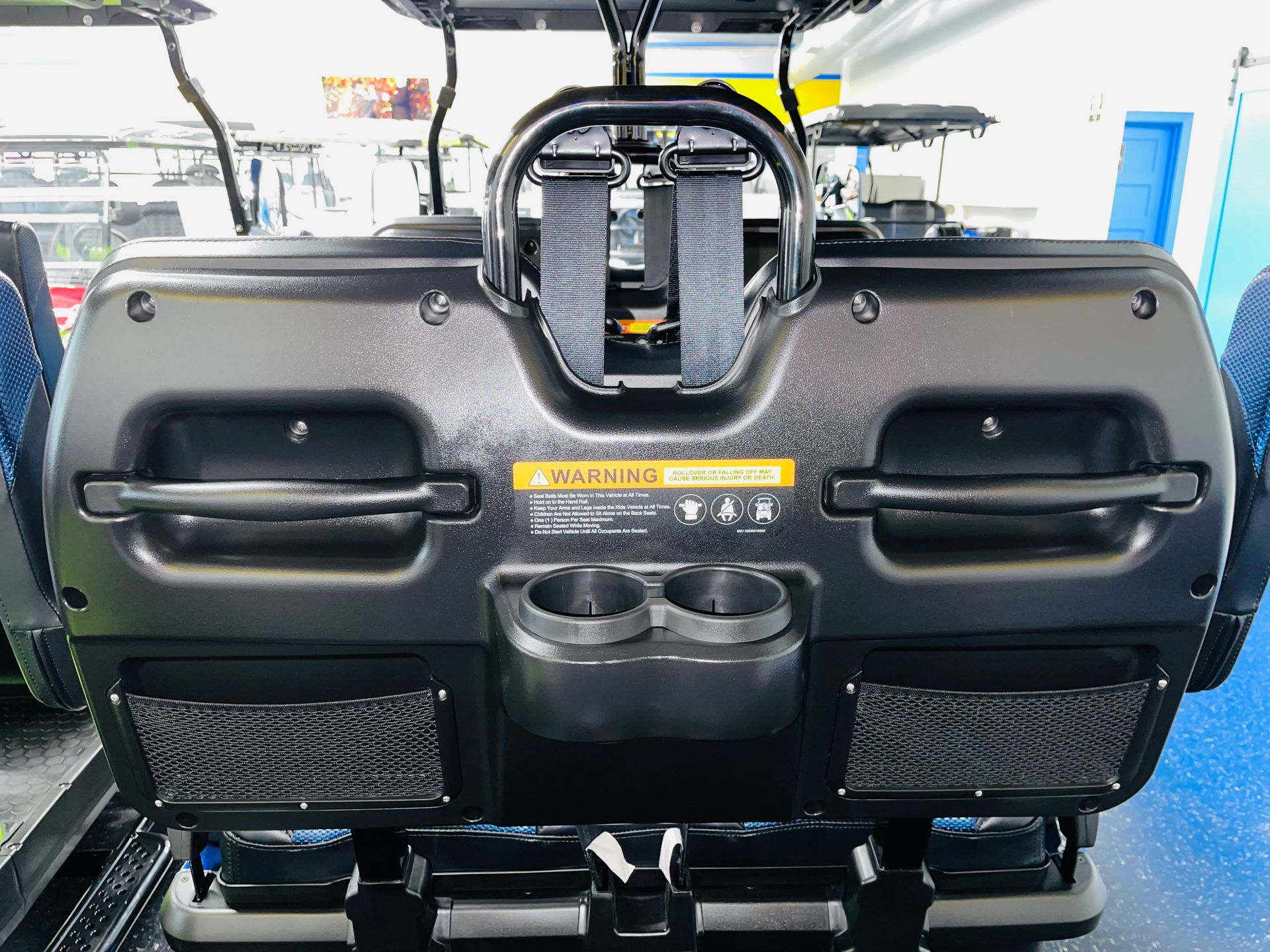 Rear view of a black scooter seat with handlebars and cup holders inside a vehicle showroom