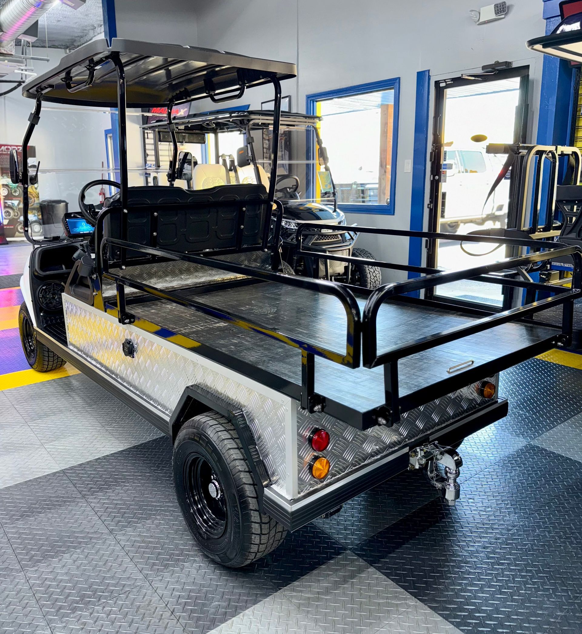 A golf cart is parked in a garage with a checkered floor.