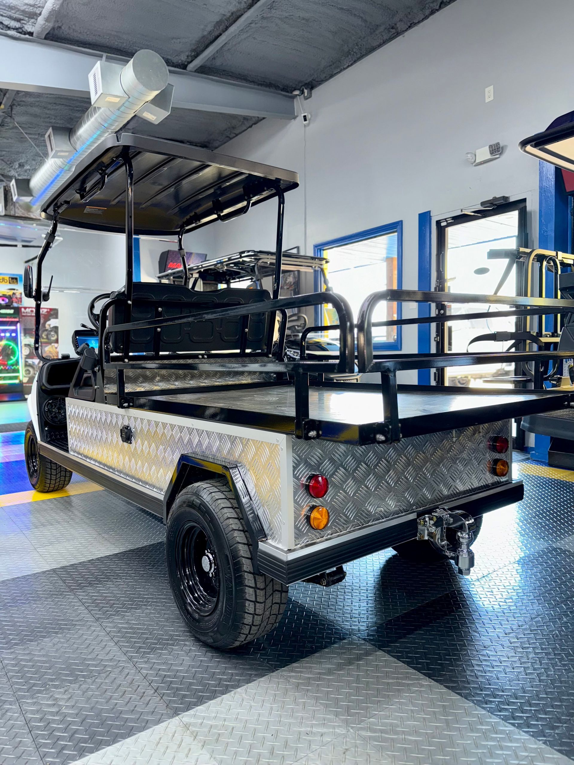 A golf cart is parked in a garage with a checkered floor.