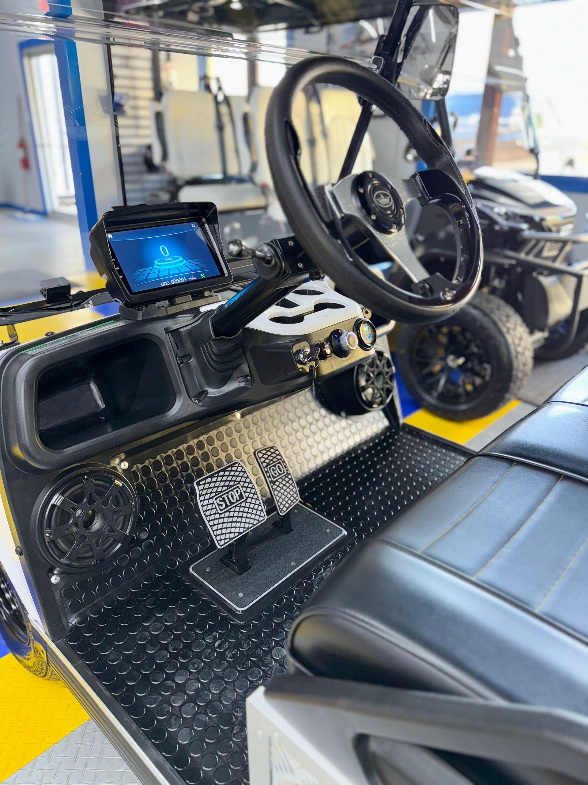 The interior of a golf cart with a steering wheel and a monitor.
