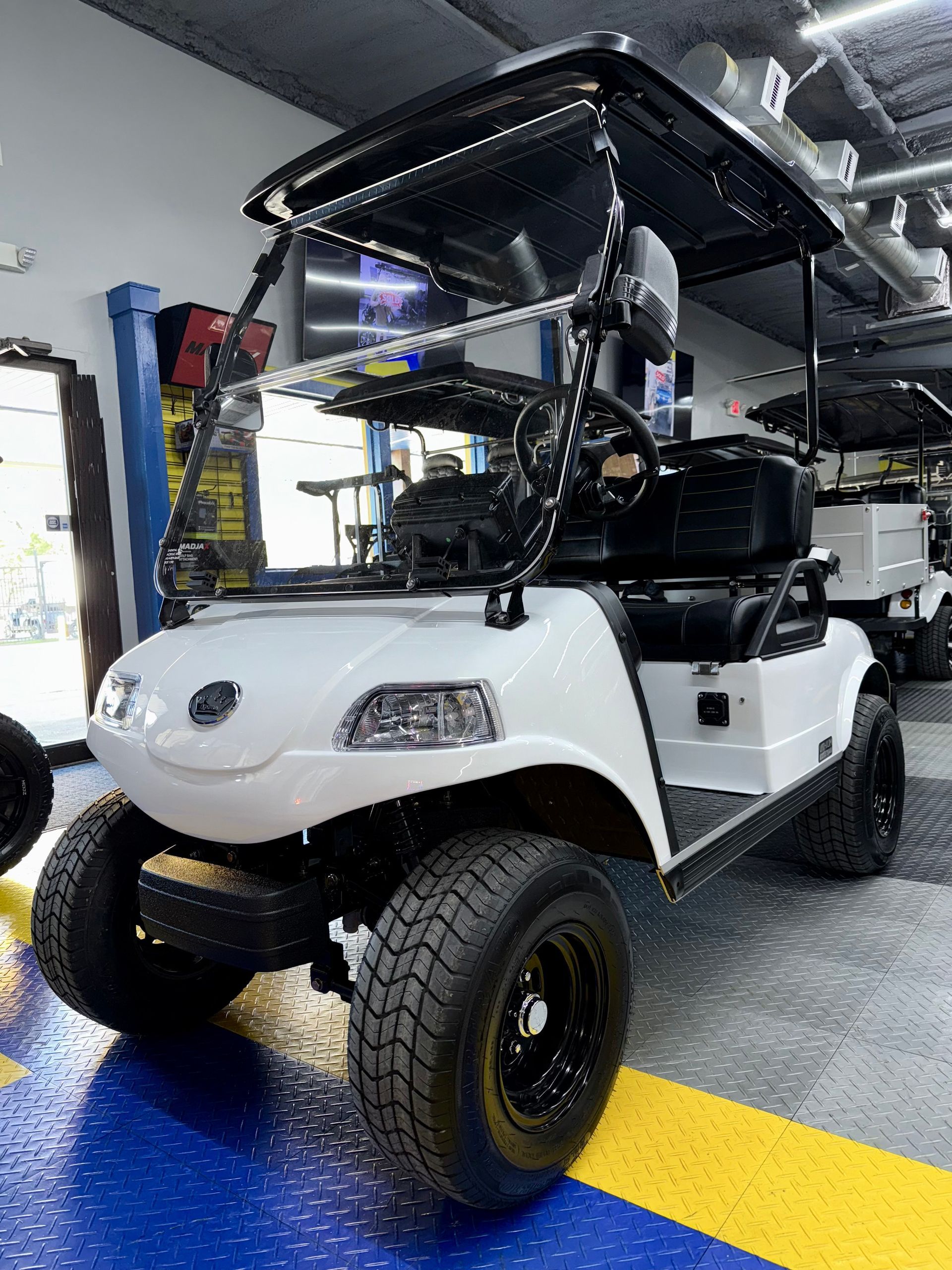 A white golf cart is parked in a garage.