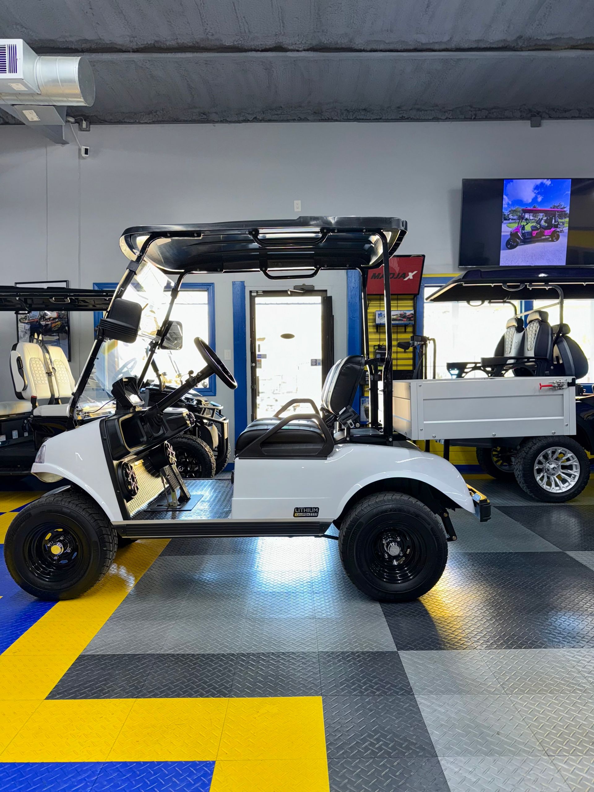 A white golf cart is parked in a garage.