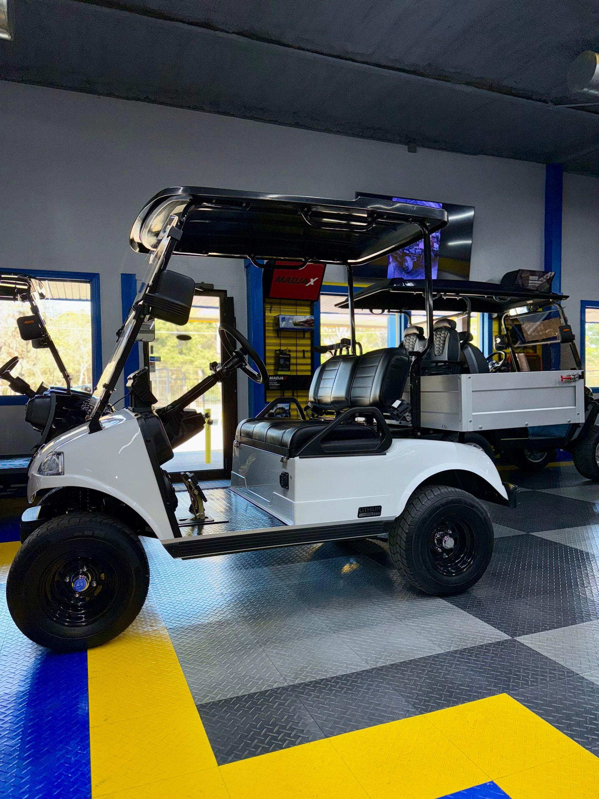 A white golf cart is parked in a garage.