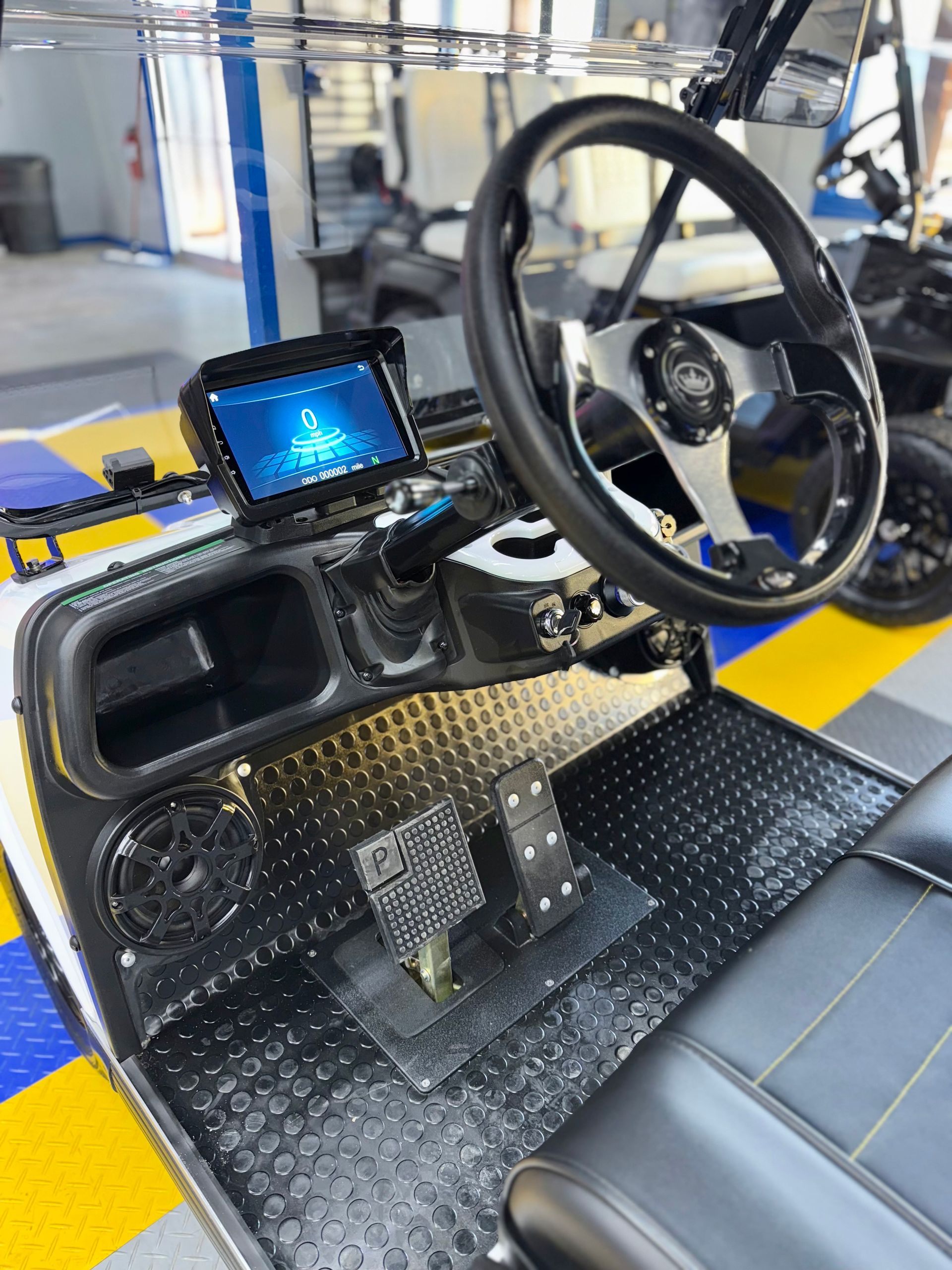 The interior of a golf cart with a steering wheel and a monitor.