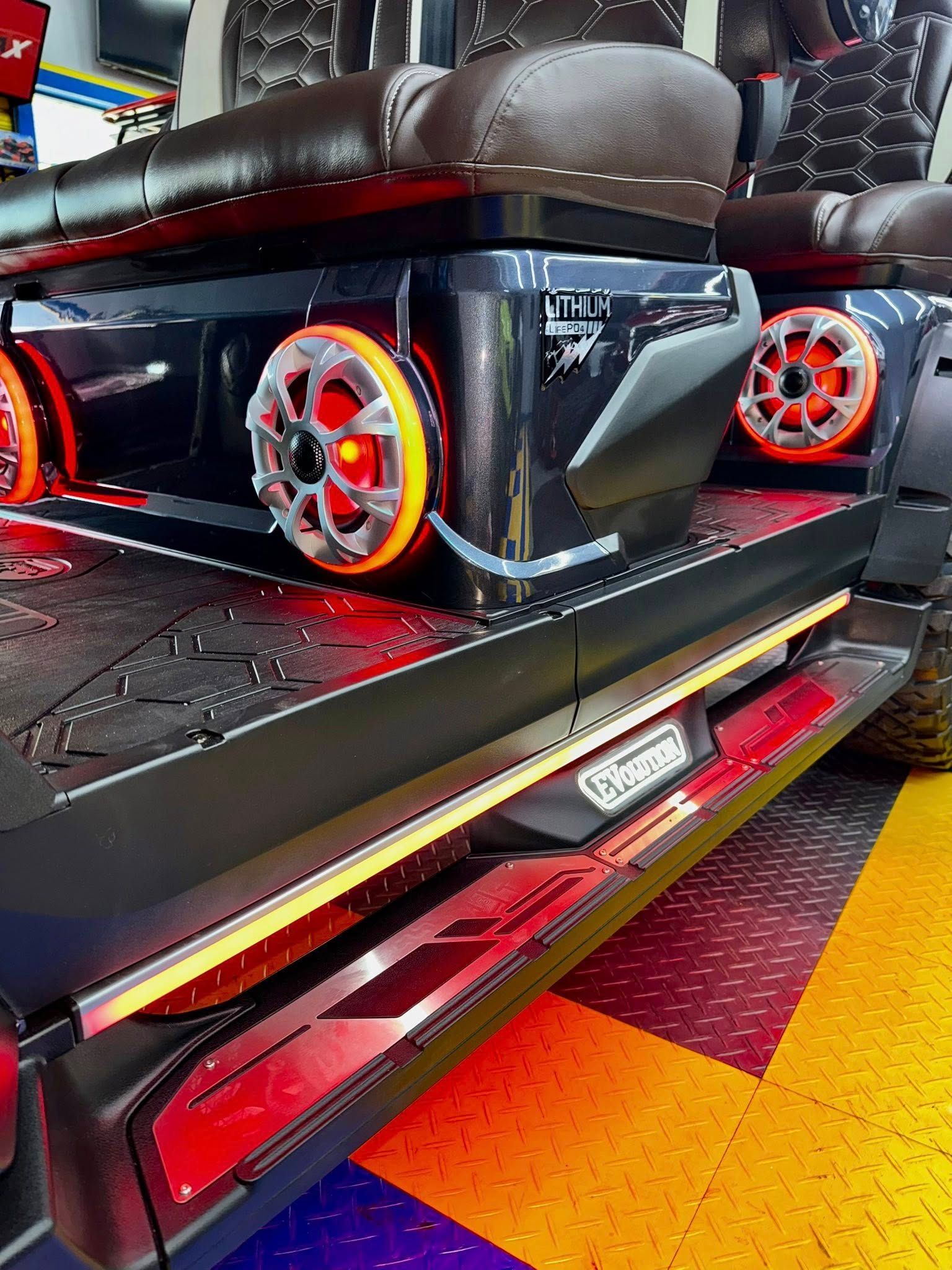 A black car with orange wheels is parked on a colorful floor.