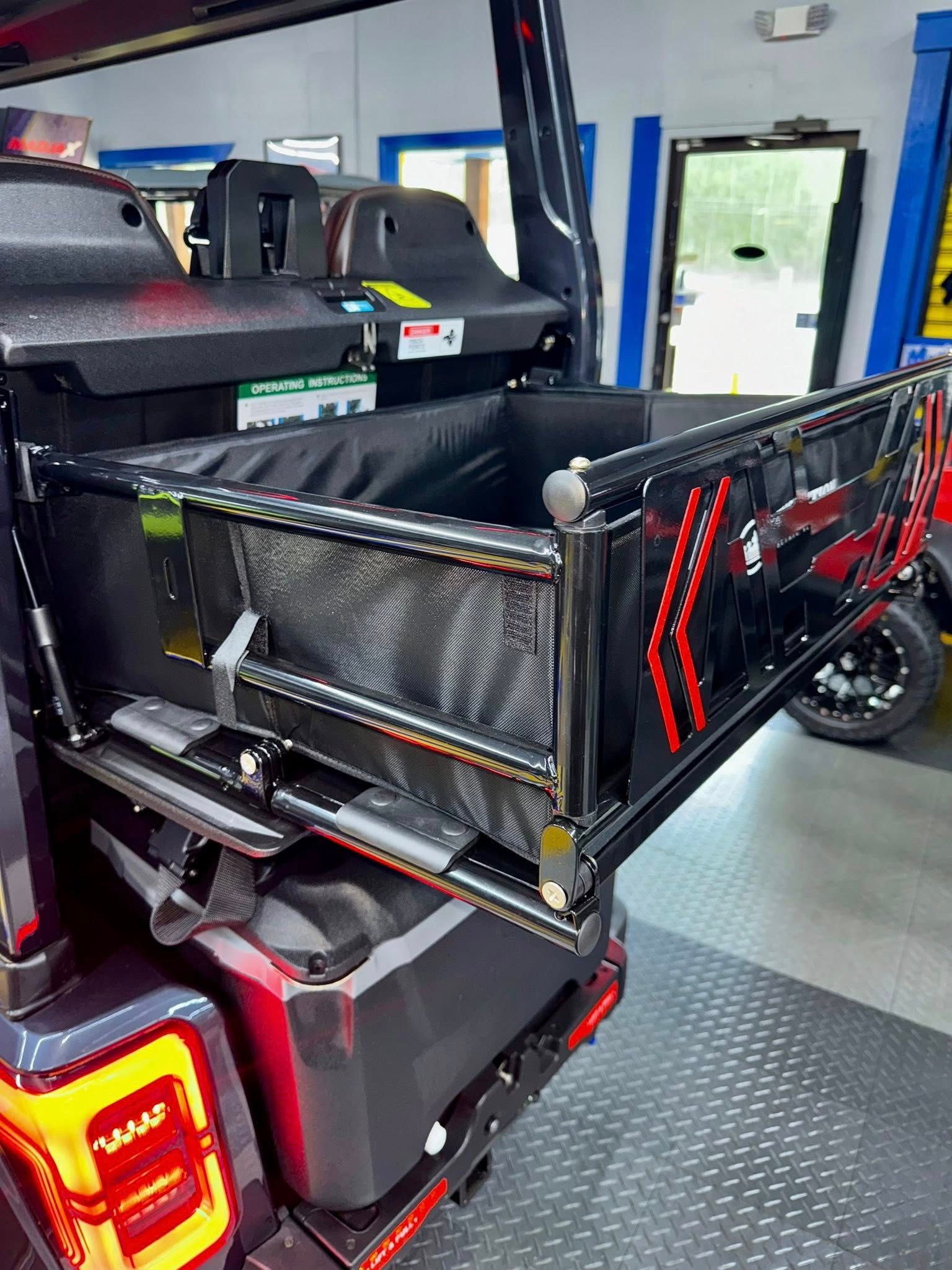 A jeep with a cargo box in the back of it is parked in a garage.