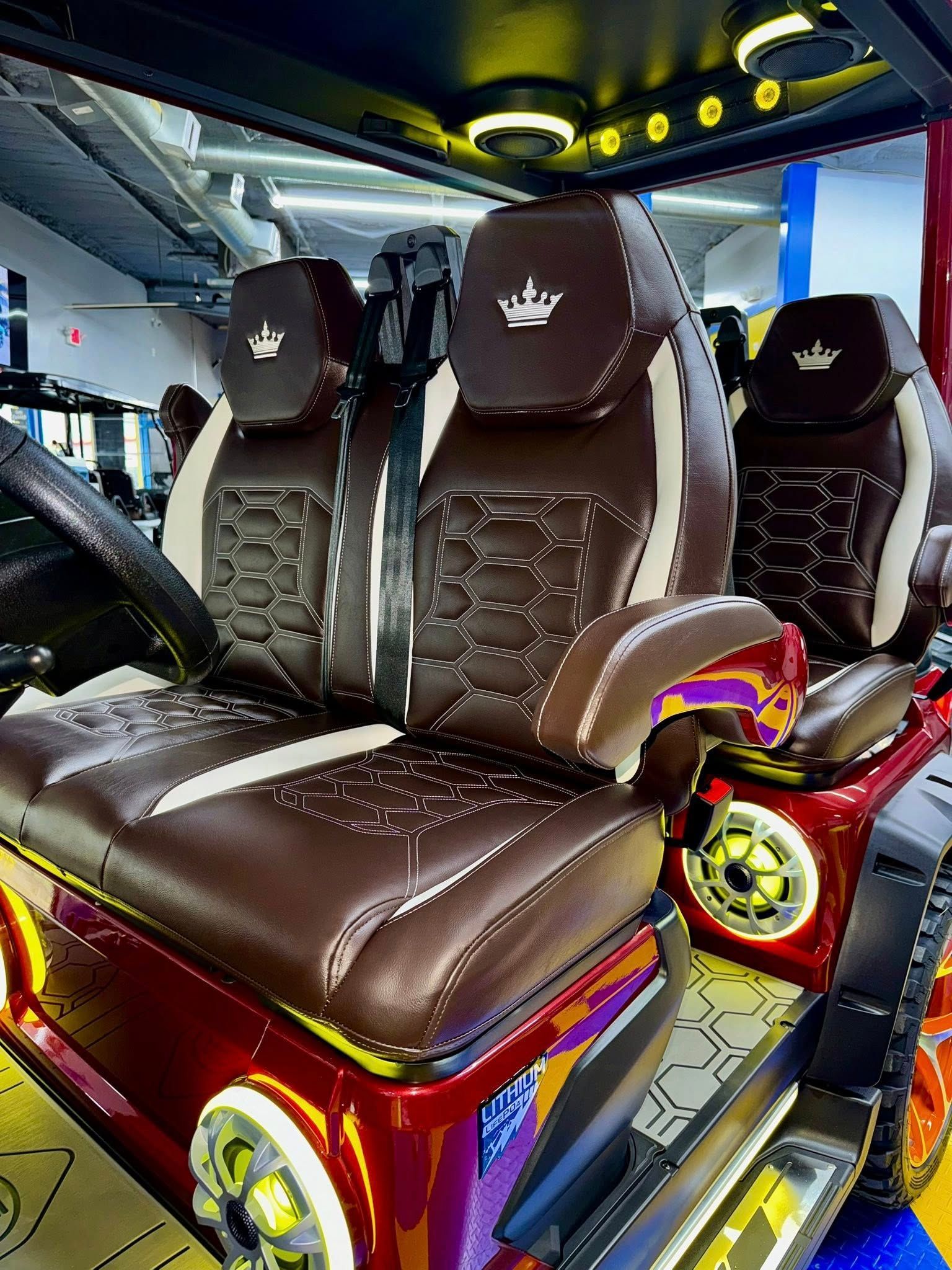 A red golf cart with brown and white seats and a crown on the back seat.