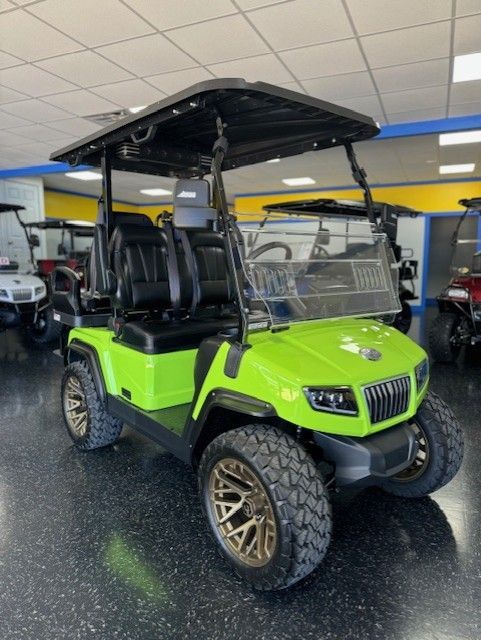 Bright green golf cart with black roof, seats, and bronze rims.  It's indoors, likely at a dealership.