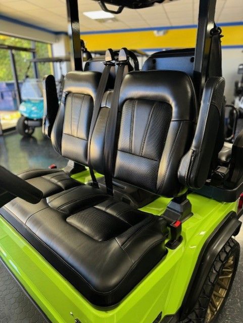 Lime green golf cart with black leather seats and seatbelts, inside a showroom.