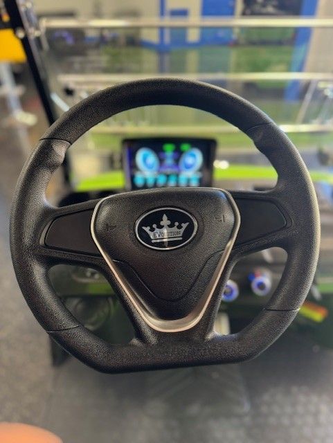 Black steering wheel with a crown logo, dashboard and display in the background.