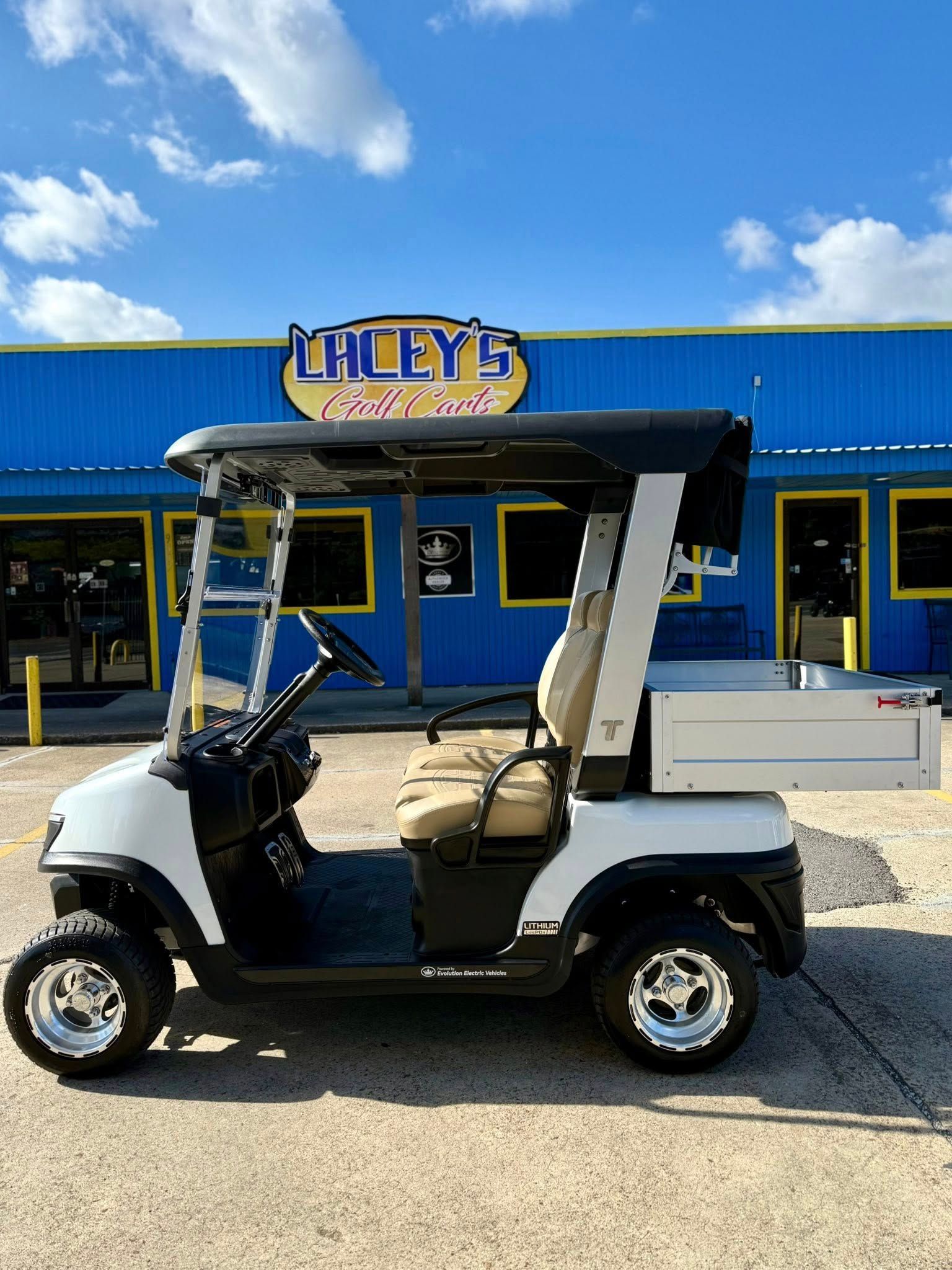 White golf cart with storage box parked in front of Lacey's Auto Parts store.