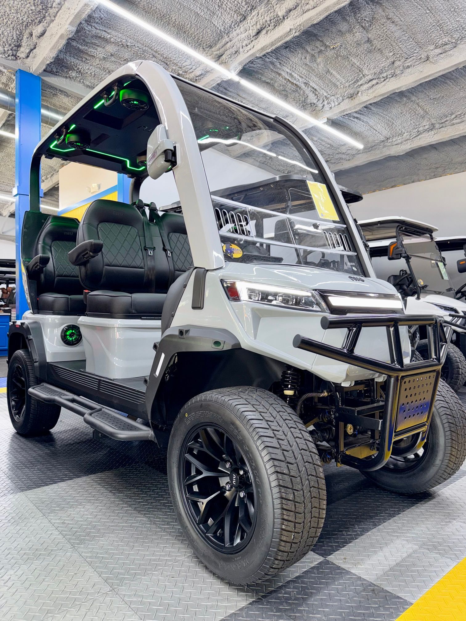 White off-road golf cart with black trim and large tires in an indoor showroom
