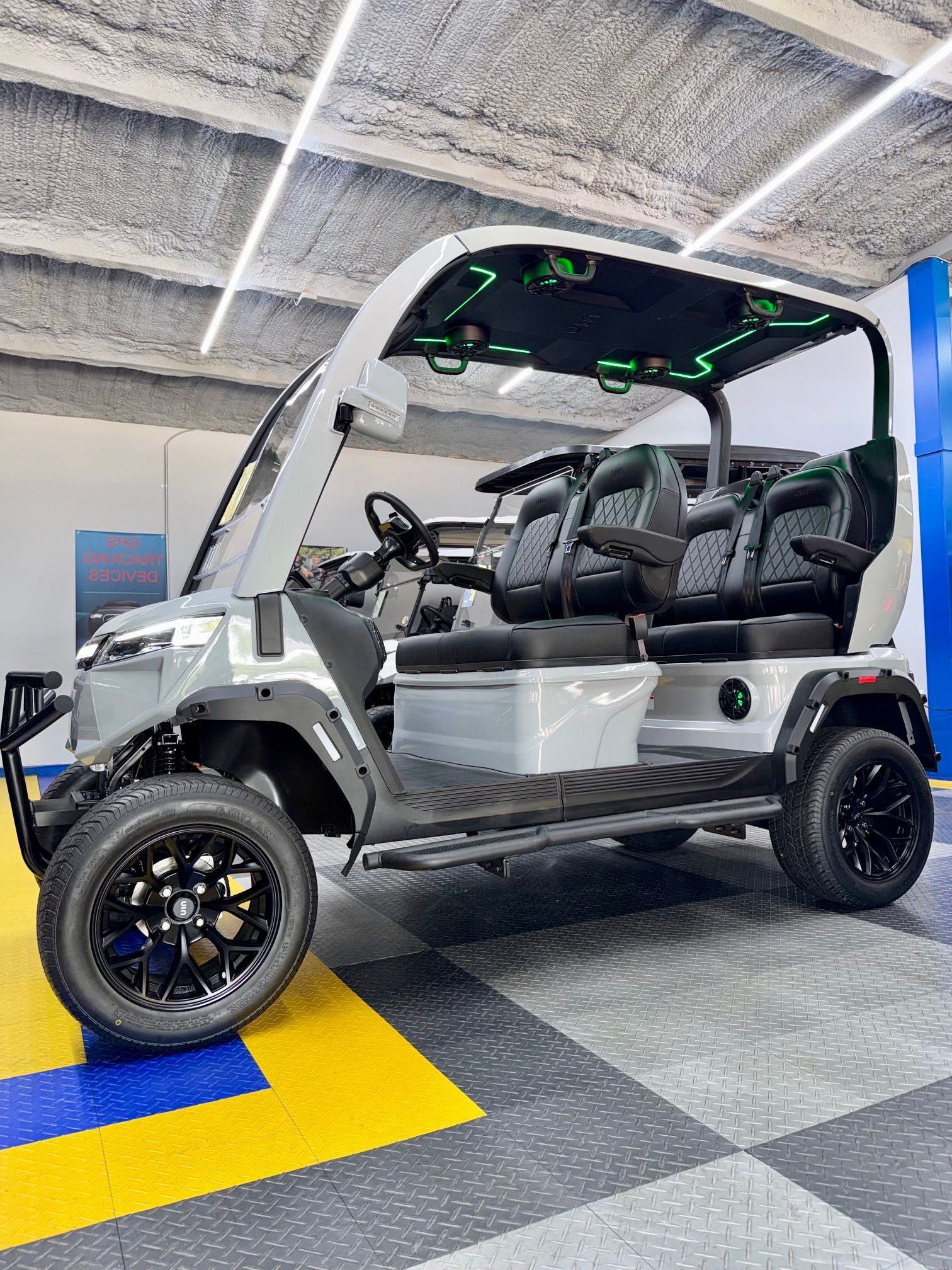 Silver off-road golf cart with black seats parked indoors on a checkered floor