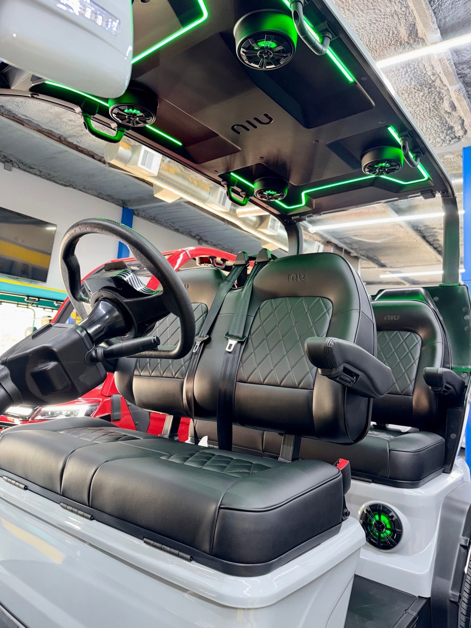 Customized car interior with white and black seats, neon green lighting, and steering wheel visible