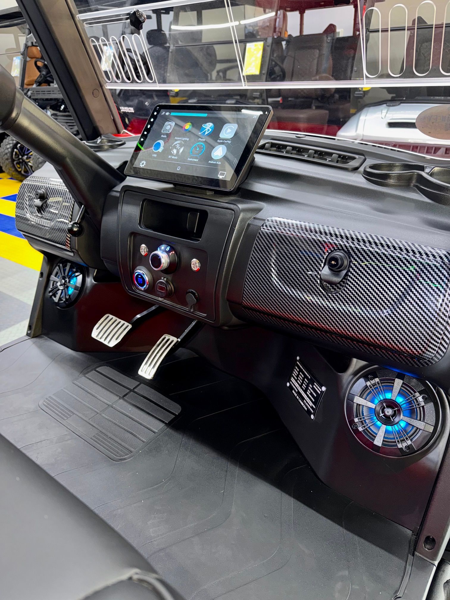 Car dashboard with carbon-fiber trim, touchscreen display, and illuminated climate controls.