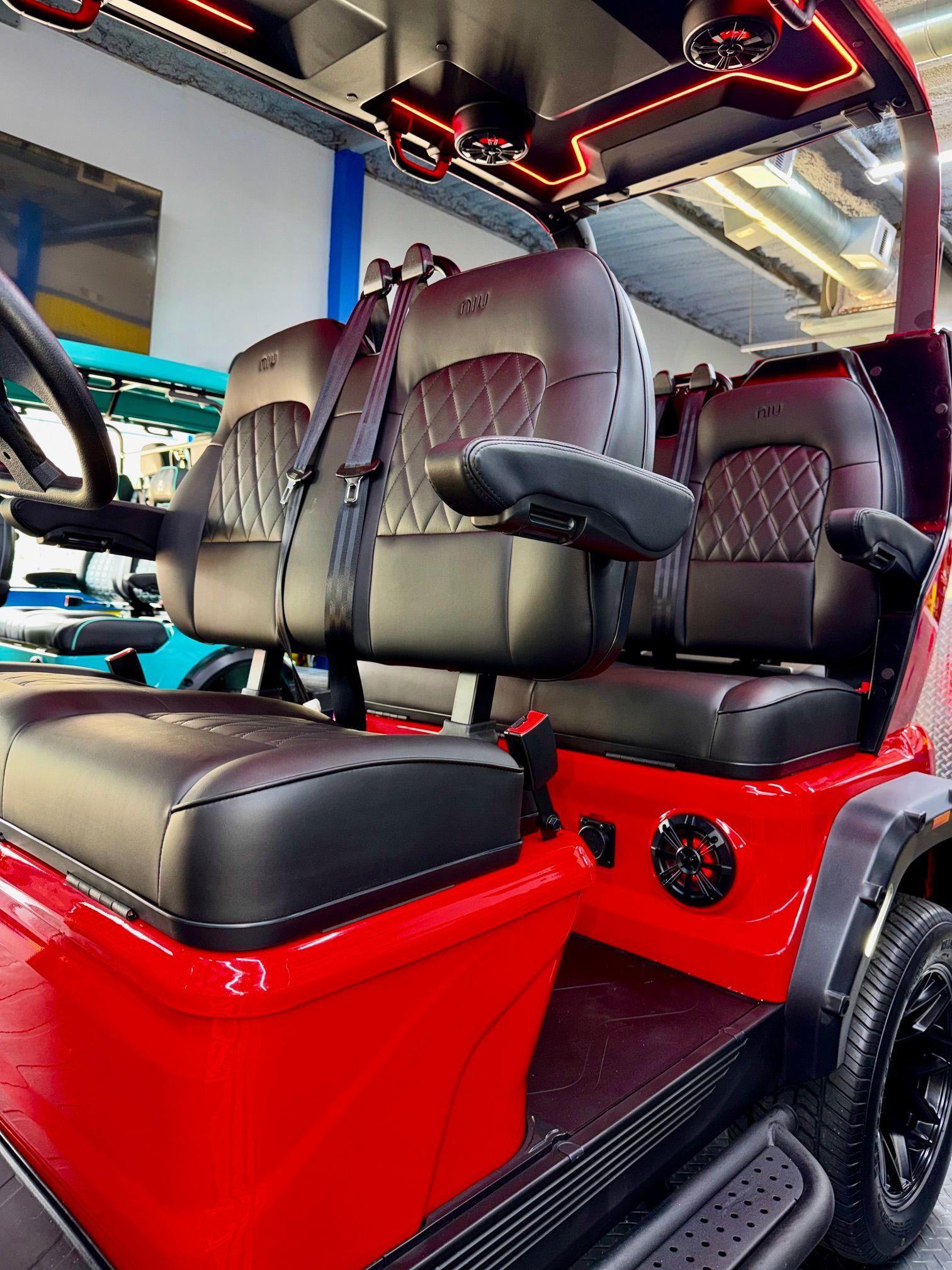 Red customized golf cart with black leather seats and LED ceiling lights, viewed from the side.