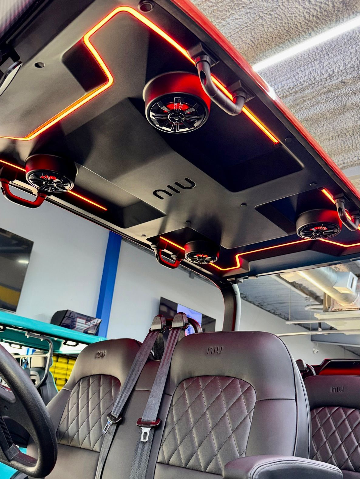 Custom car roof with orange LED lighting and speakers above quilted front seats.