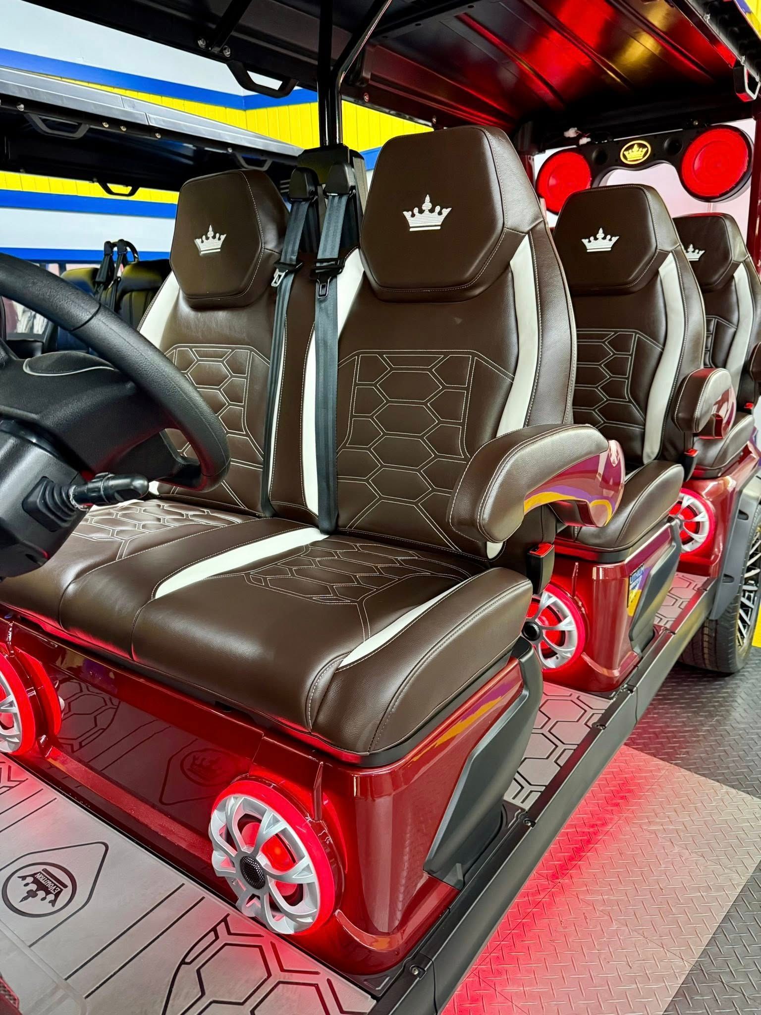 A luxury golf cart interior with brown and white leather seats, red accents, and LED lights.