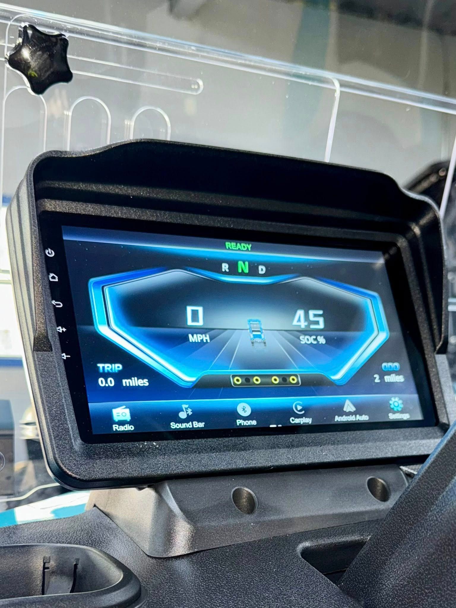 Dashboard display showing speed of 45 mph, gear selection, and other vehicle information. The screen is housed in a protective black frame.