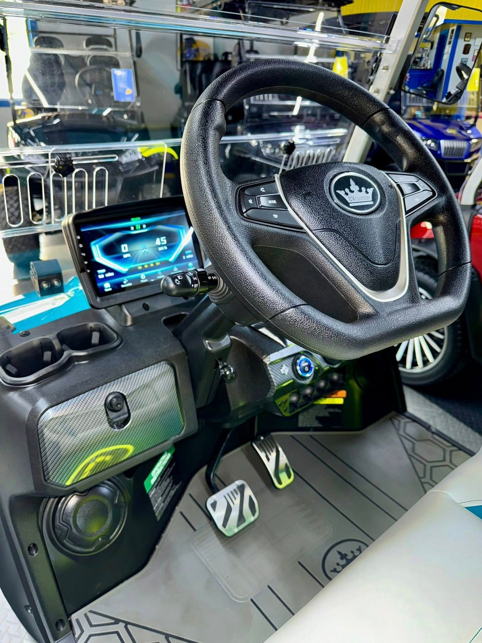 Interior of a custom golf cart with a black and silver dashboard, a touch screen, and a stylish steering wheel.