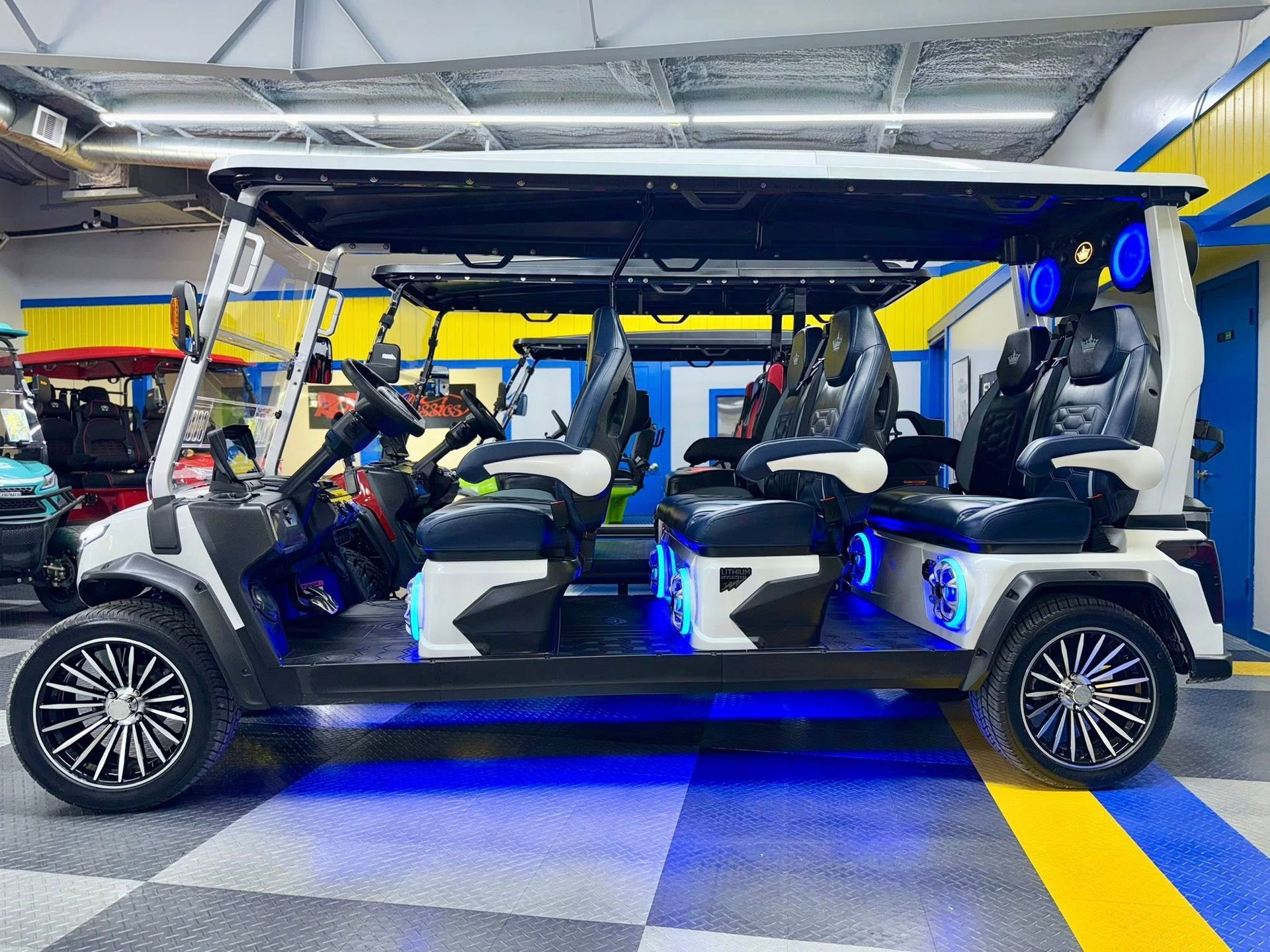 A golf cart with a lot of seats is parked in a garage.