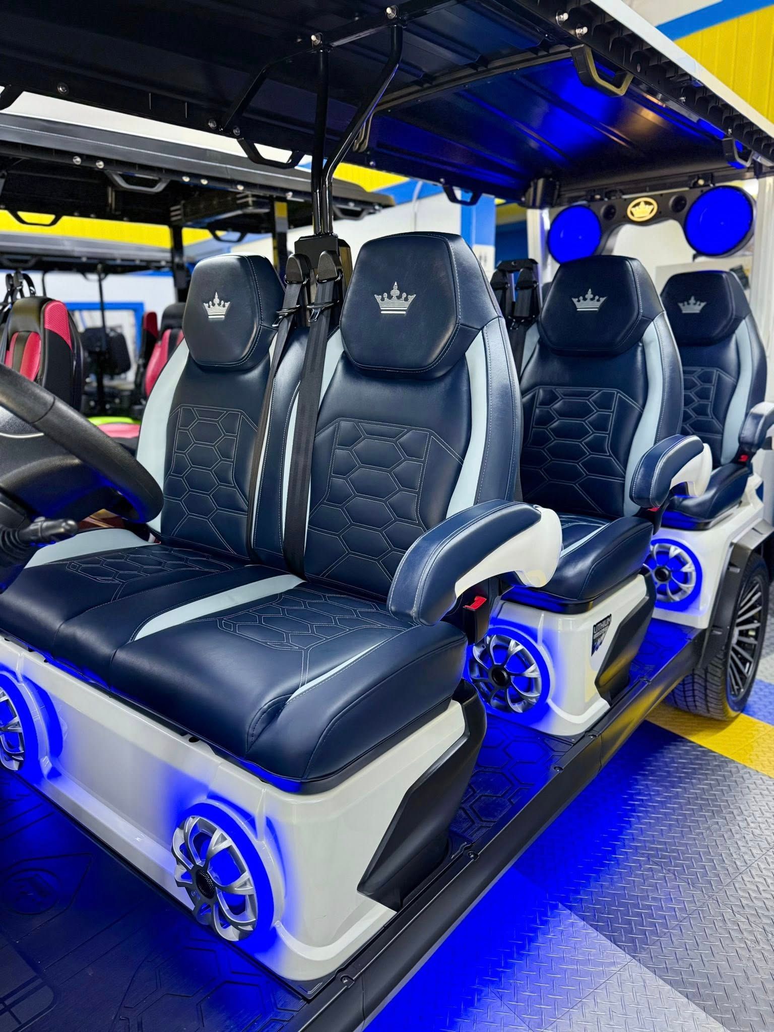 The inside of a golf cart with black and white seats and blue lights.