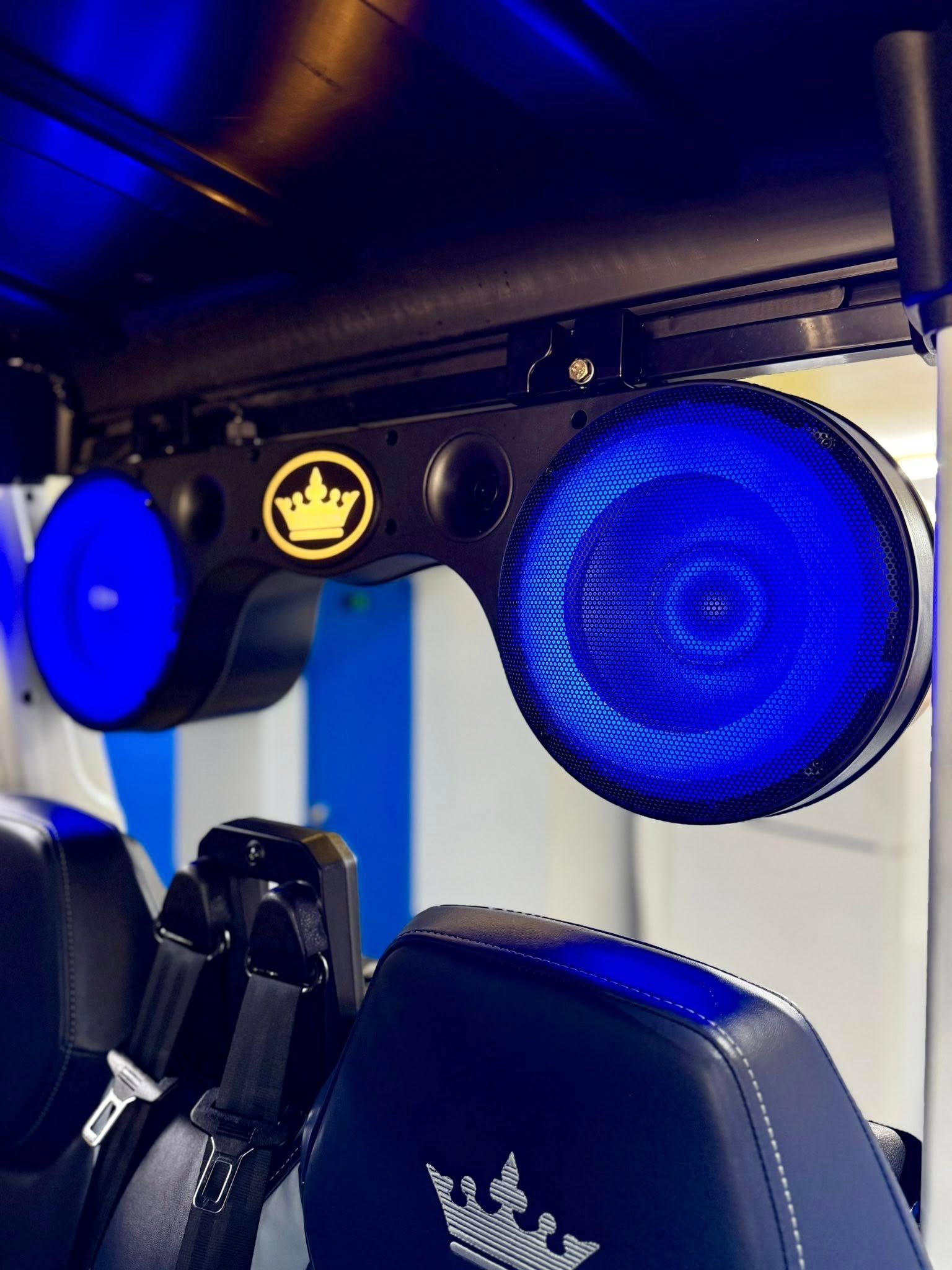 A pair of speakers with a crown on them are hanging from the ceiling of a vehicle.