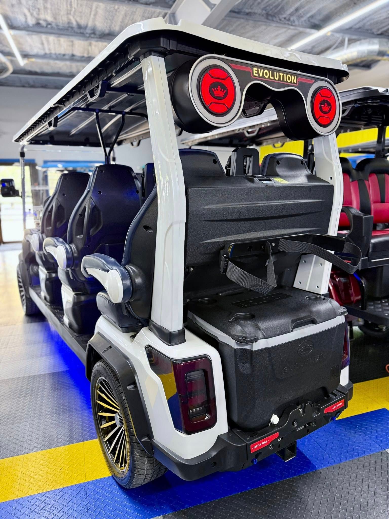 A golf cart with speakers on the back is parked in a garage.