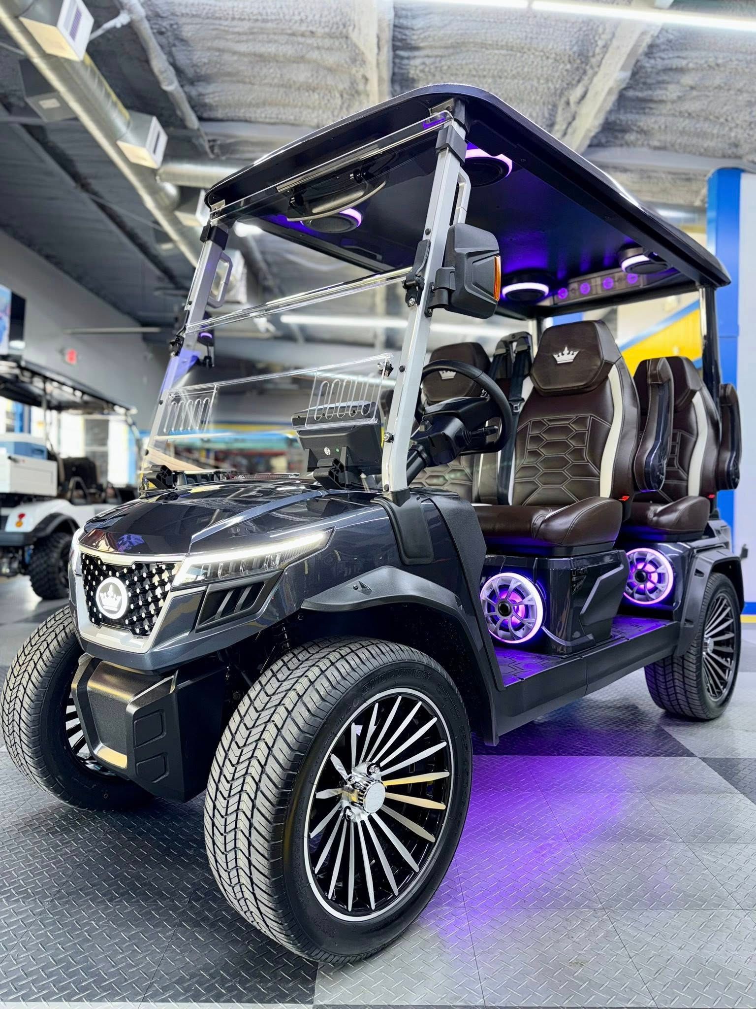 A black golf cart with purple lights is parked in a garage.