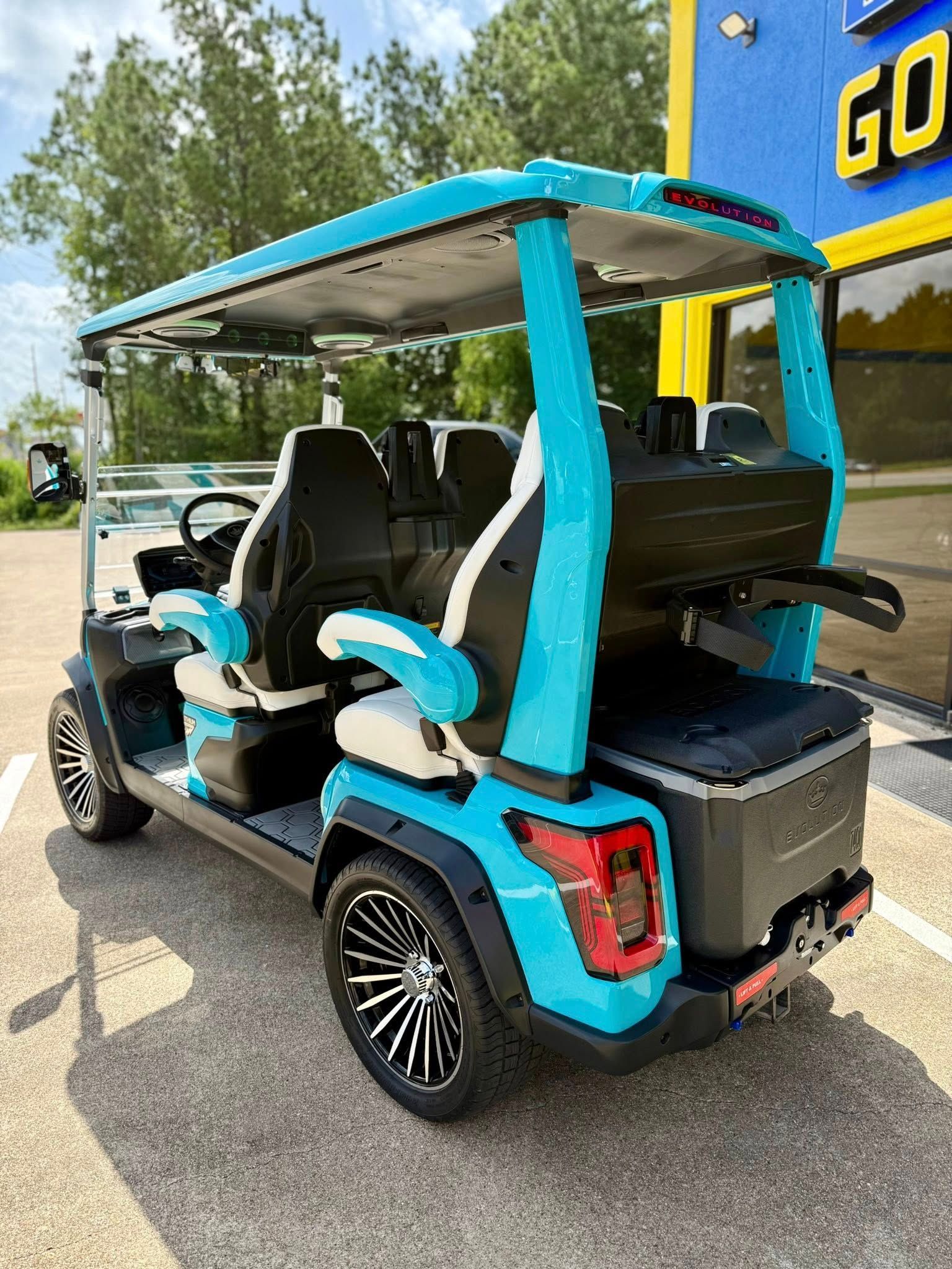 A blue golf cart is parked in a parking lot in front of a building.