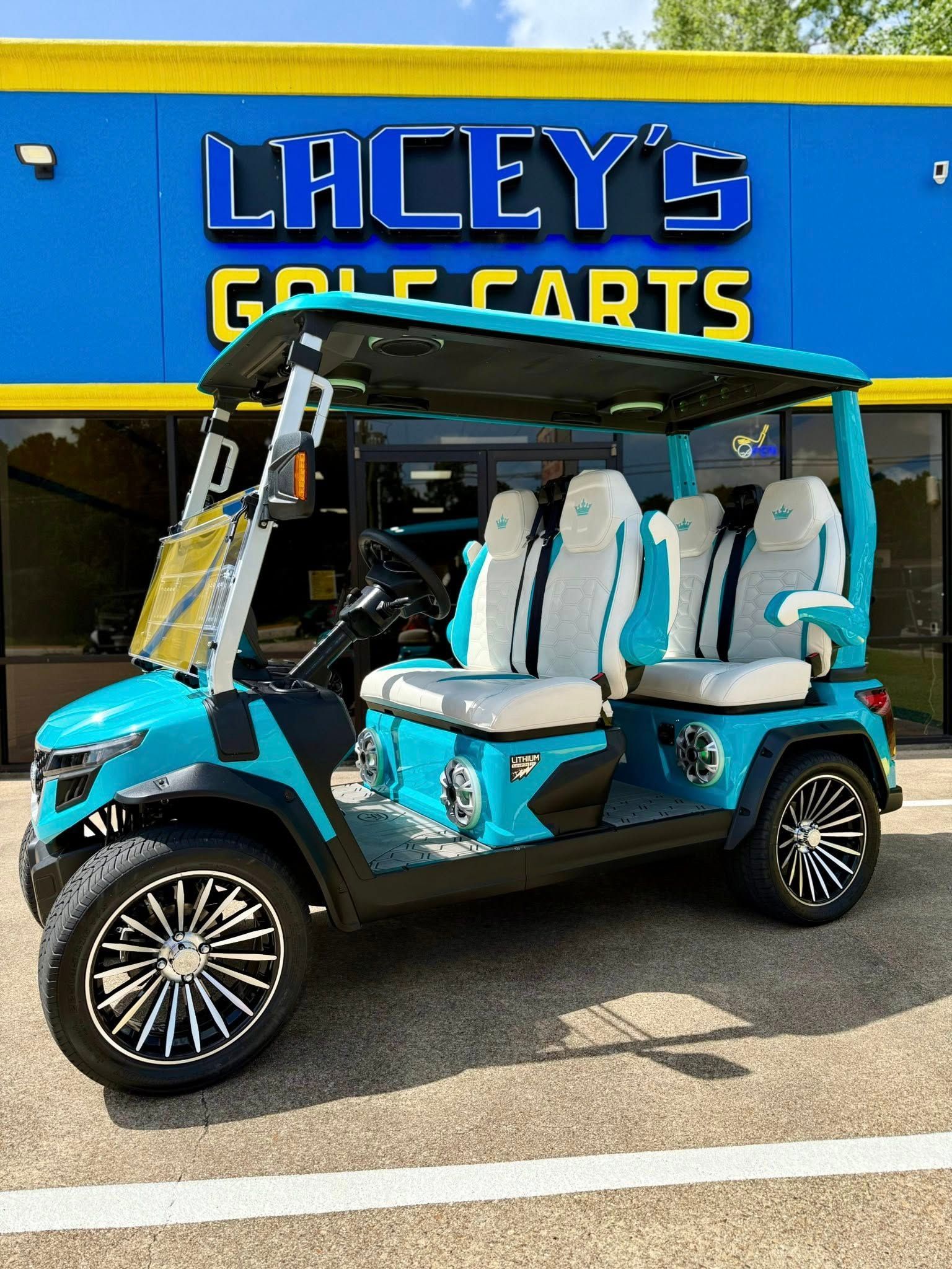 A blue golf cart is parked in front of a lacey 's golf carts store.